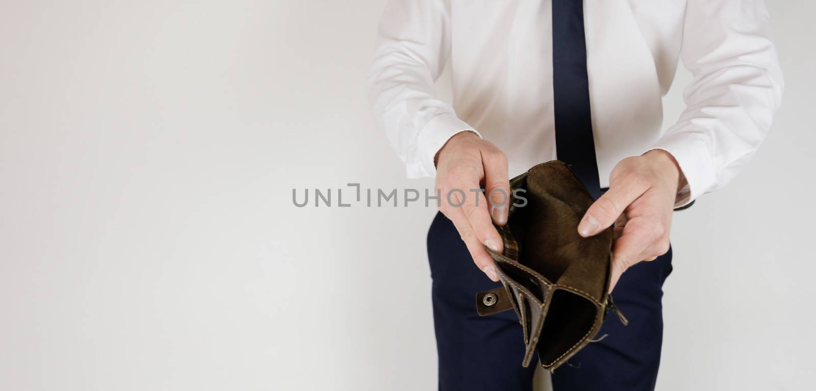 A man in a business suit holds in his hands an empty wallet without money. Financial crisis. Bankruptcy in business. The employer is disappointed.