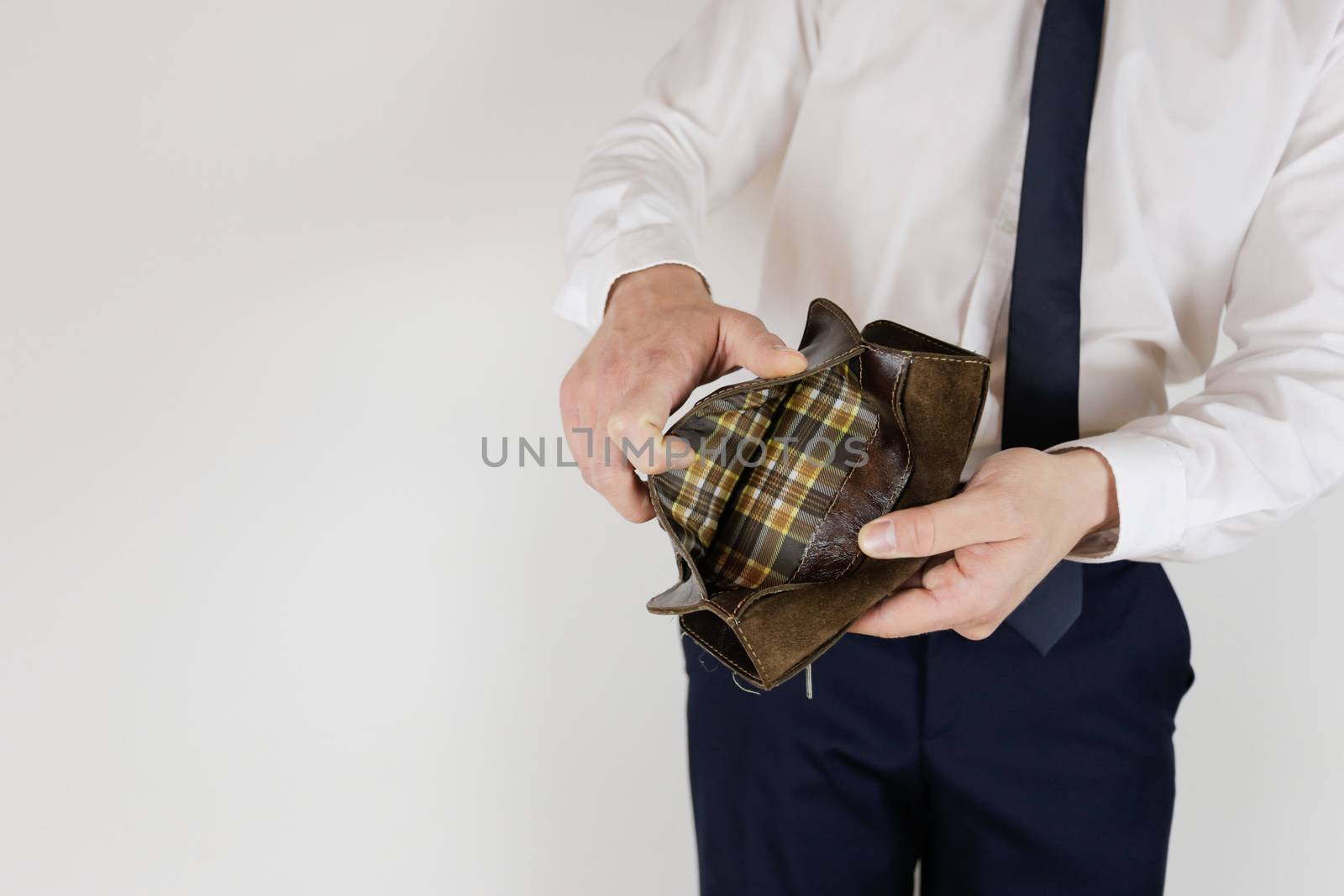 A man in a business suit holds in his hands an empty wallet without money. Financial crisis. Bankruptcy in business. The employer is disappointed.