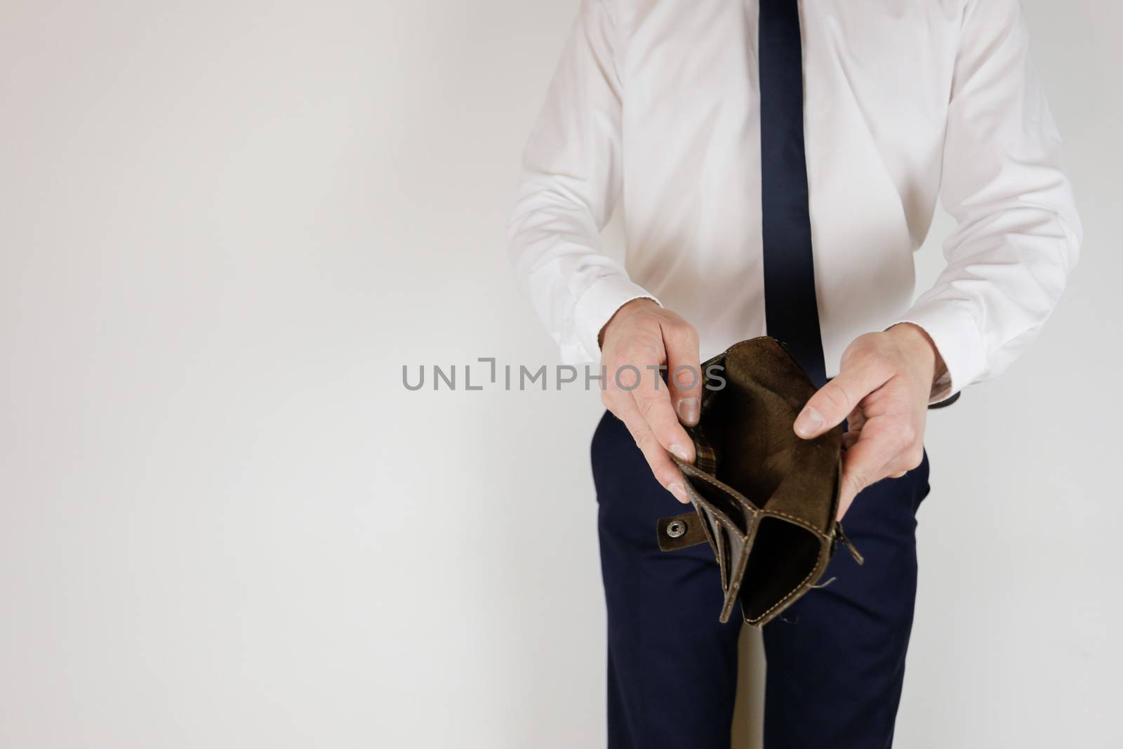 A man in a business suit holds in his hands an empty wallet without money. Financial crisis. Bankruptcy in business. The employer is disappointed.