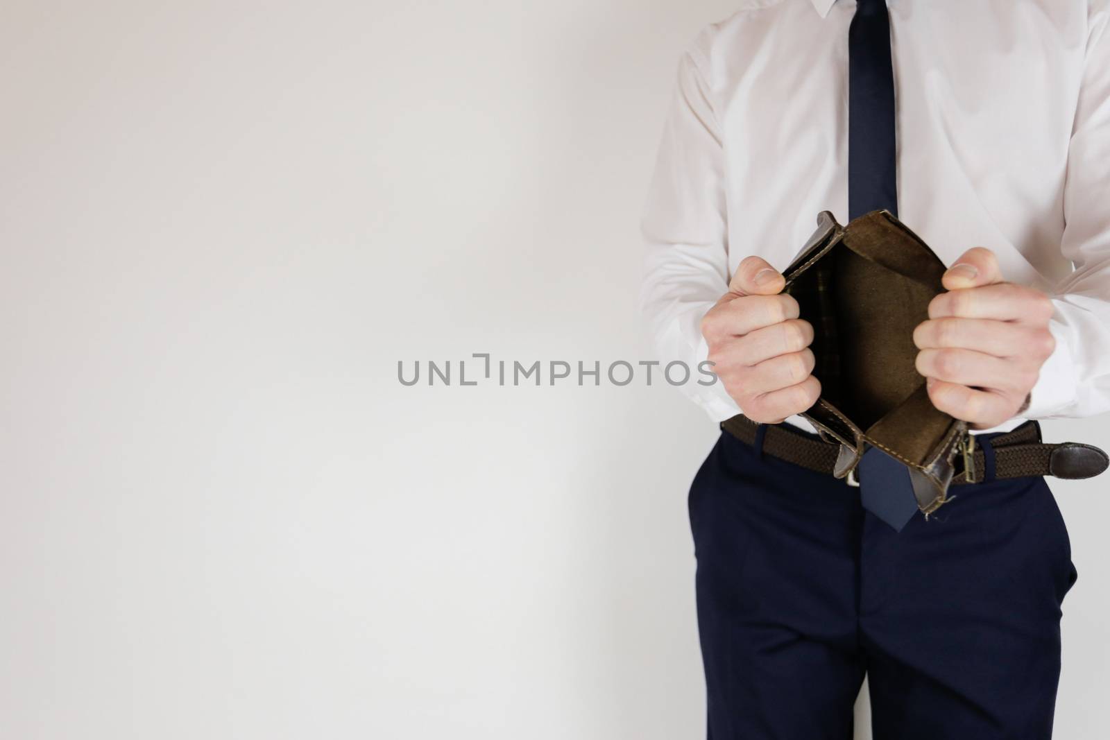 A man in a business suit holds in his hands an empty wallet without money. Financial crisis. Bankruptcy in business. The employer is disappointed.