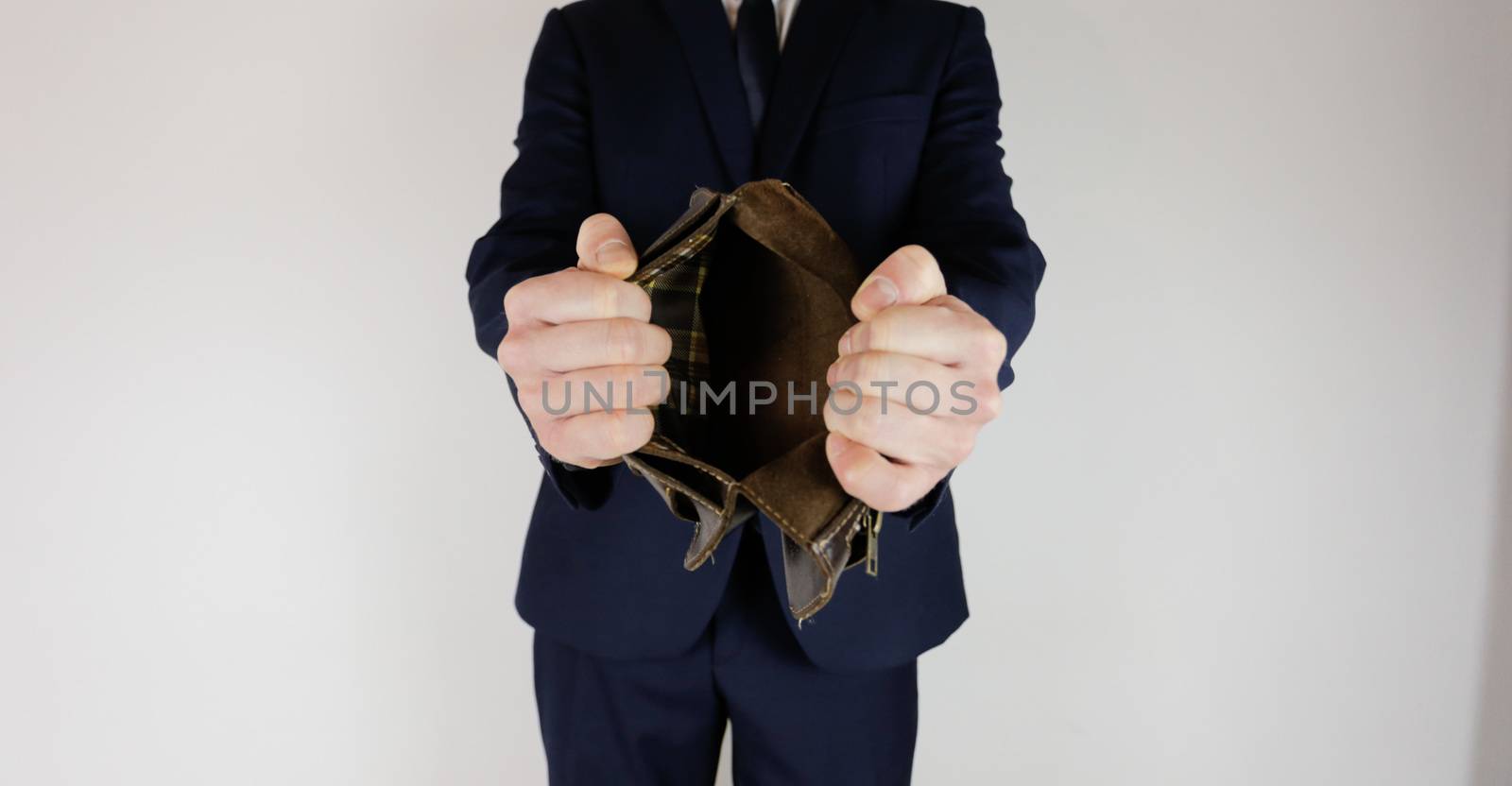 A man in a business suit holds in his hands an empty wallet without money. Financial crisis. Bankruptcy in business. The employer is disappointed.