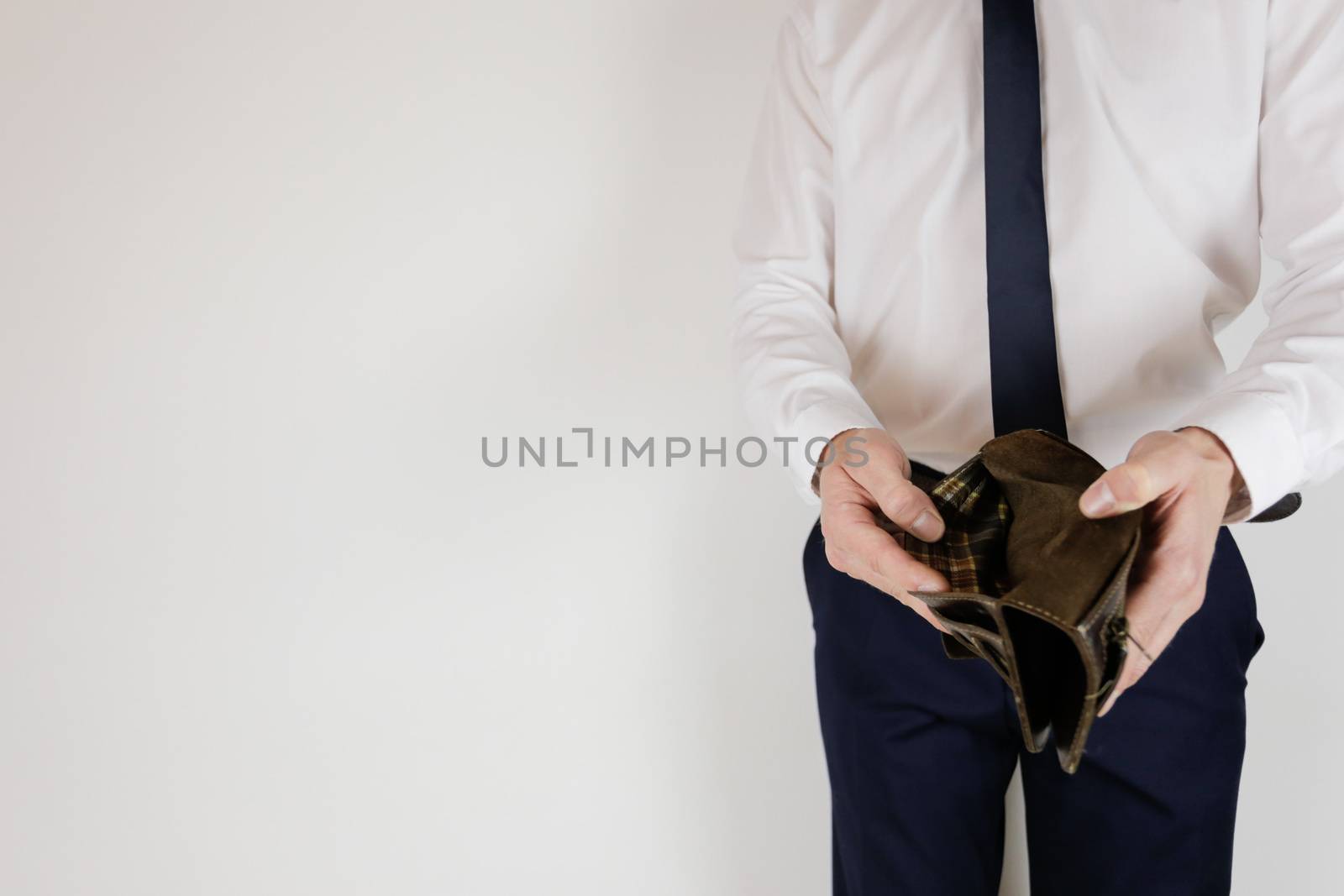 A man in a business suit holds in his hands an empty wallet without money. Financial crisis. Bankruptcy in business. The employer is disappointed.