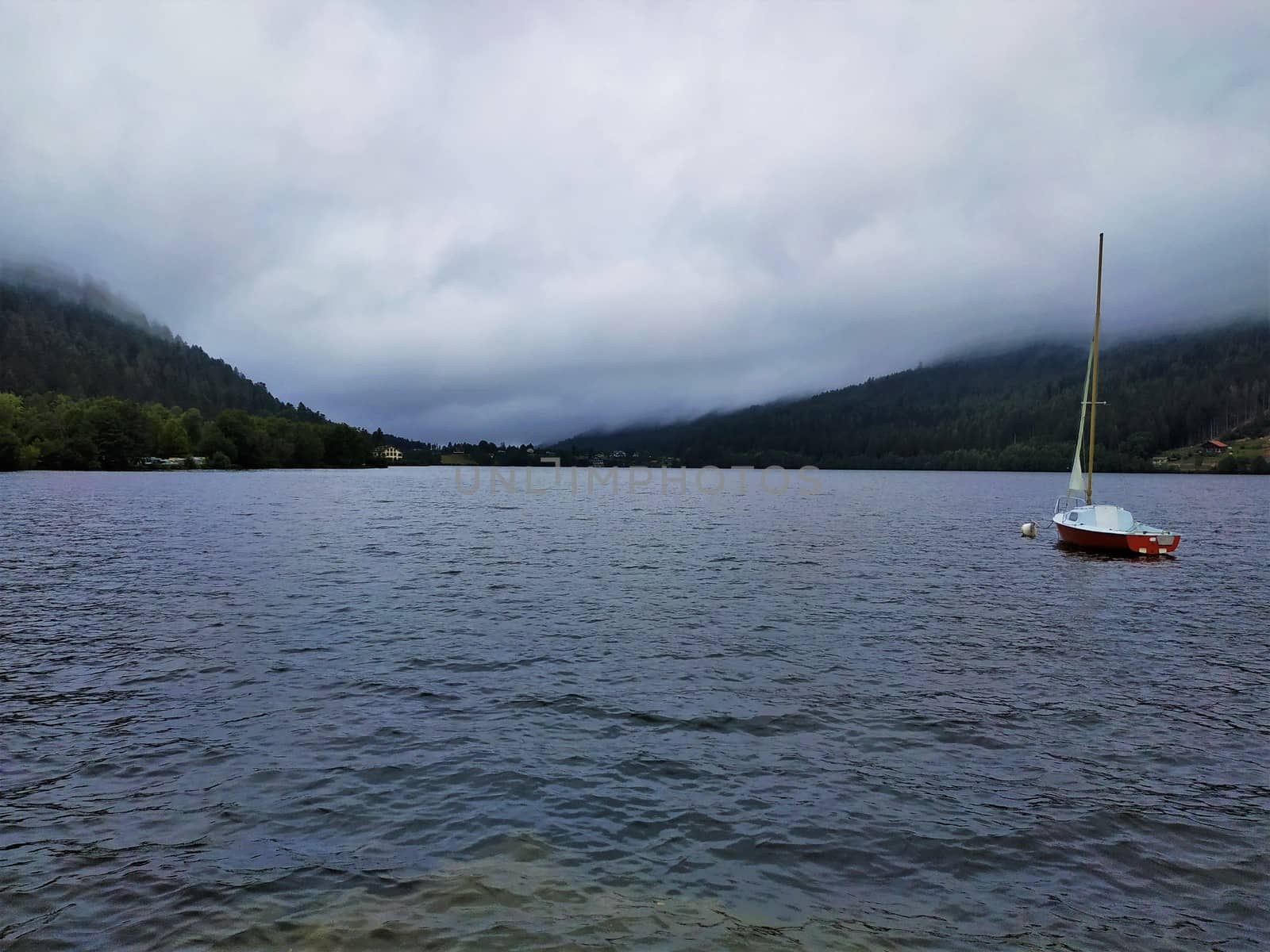 Dramatic scene of a boat on the lake in Gerardmer on a cloudy and stormy day by pisces2386