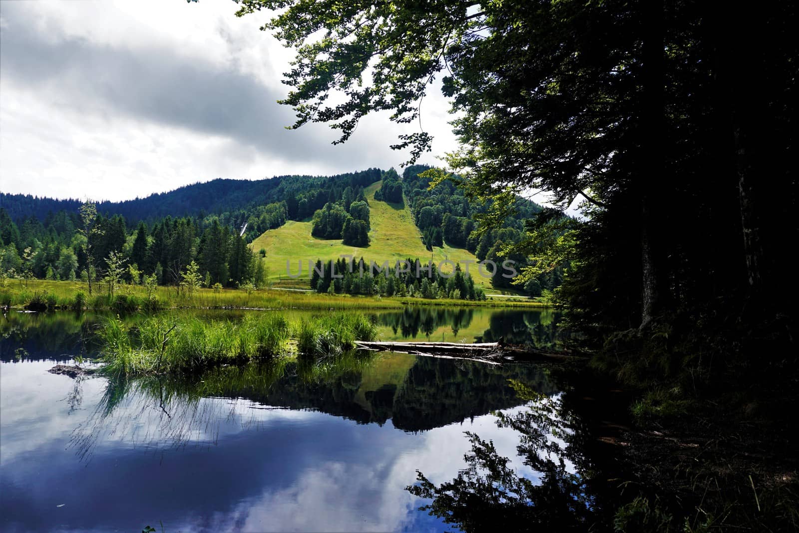 View over Lispach lake in La Bresse, France to hills with slope