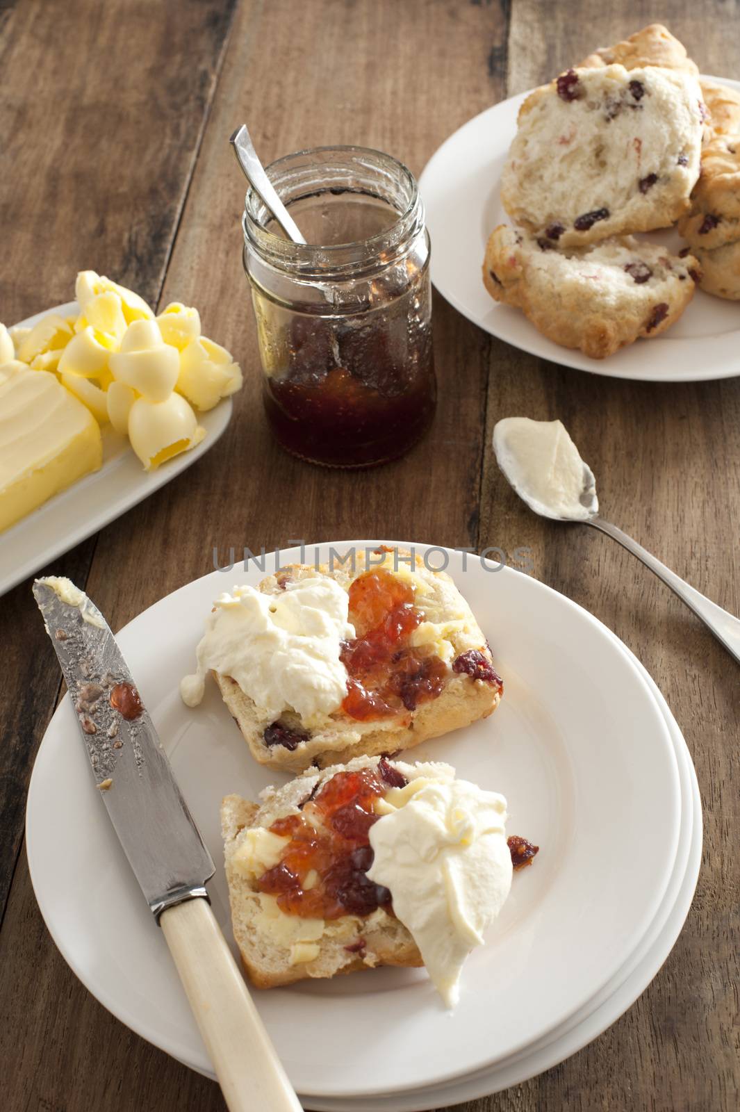 Fresh buttered rock cake with cream and fruit jam by stockarch