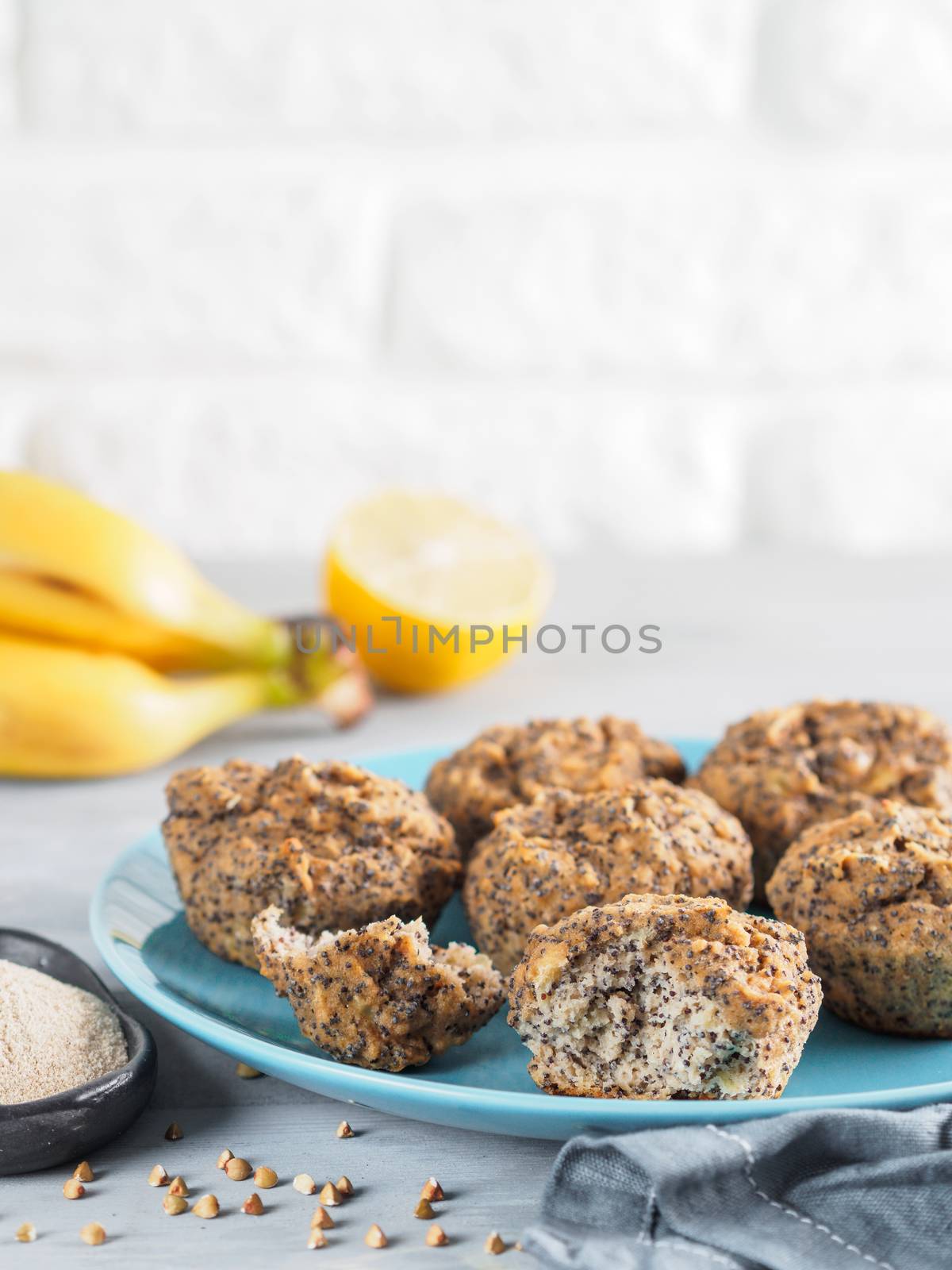 Close-up view of healthy gluten-free homemmade banana muffins with buckwheat flour. Vegan muffins with poppy seeds on blue plate over gray wooden table. Copy space