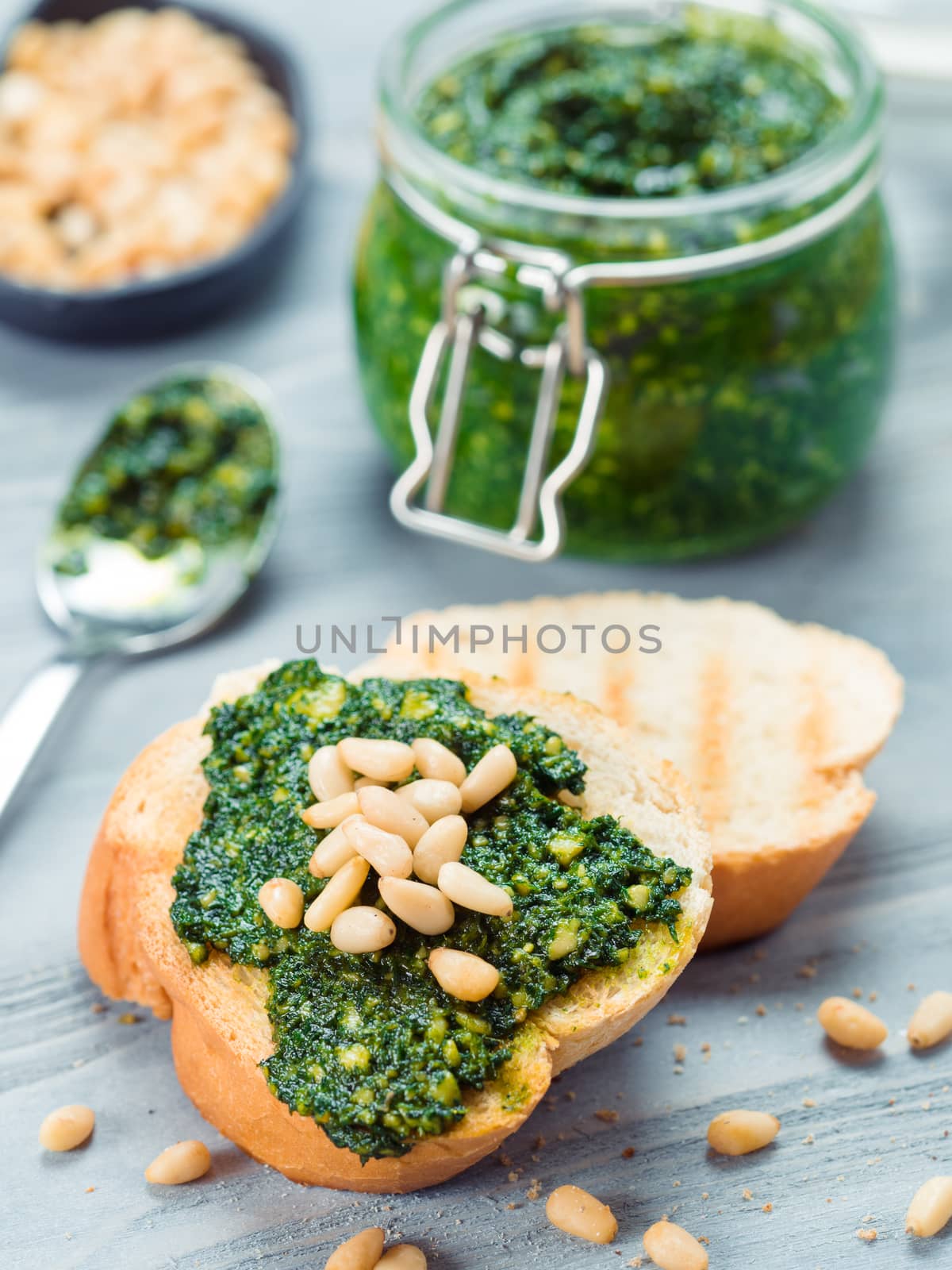 Close up view of baguette bread with fresh basil pesto sauce on gray wooden table. Copy space.