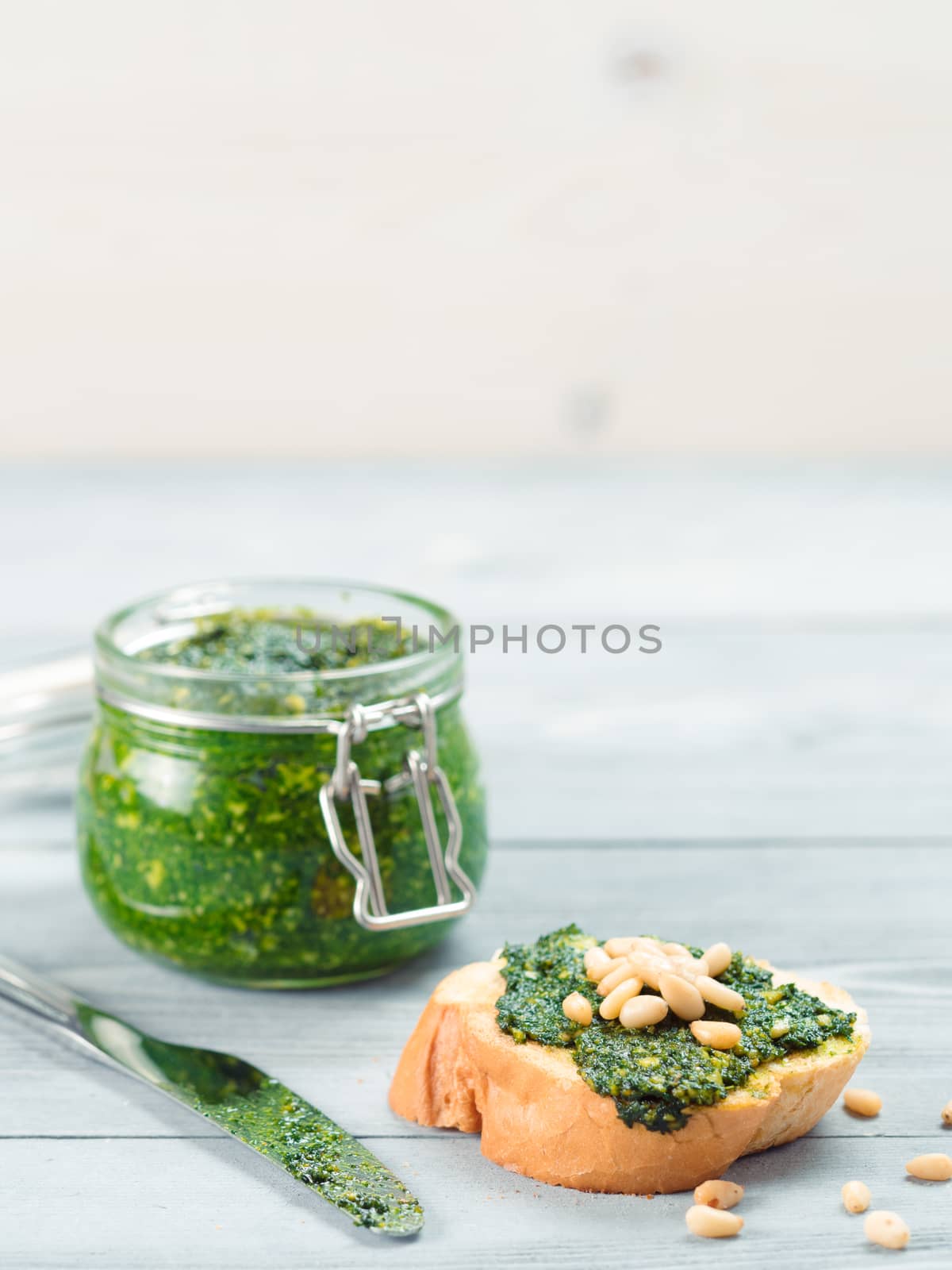 Close up view of baguette bread with fresh basil pesto sauce on gray wooden table. Copy space.