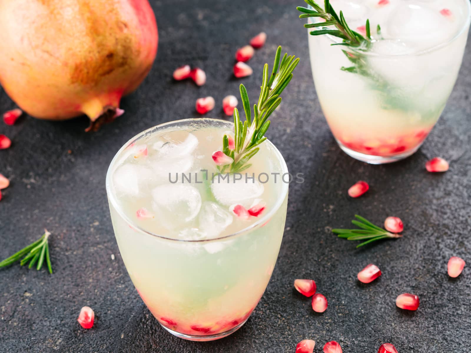 Autumn and winter cocktails idea - white sangria with rosemary, pomegrante and lemon juice and ingredients on black cement background.