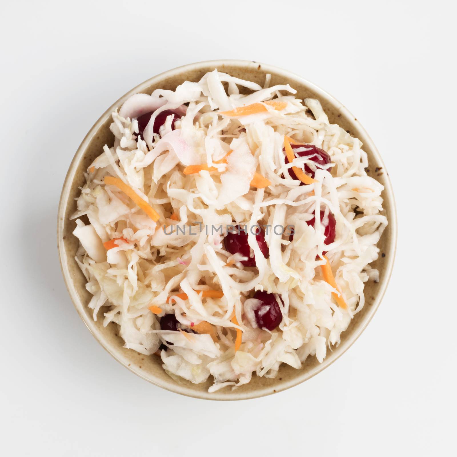 Traditional russian appetizer sauerkraut with cranberry and carrot in craft plate isolated on white. Fermented cabbage. Russian cuisine and russian kitchen. Top view or flat-lay.