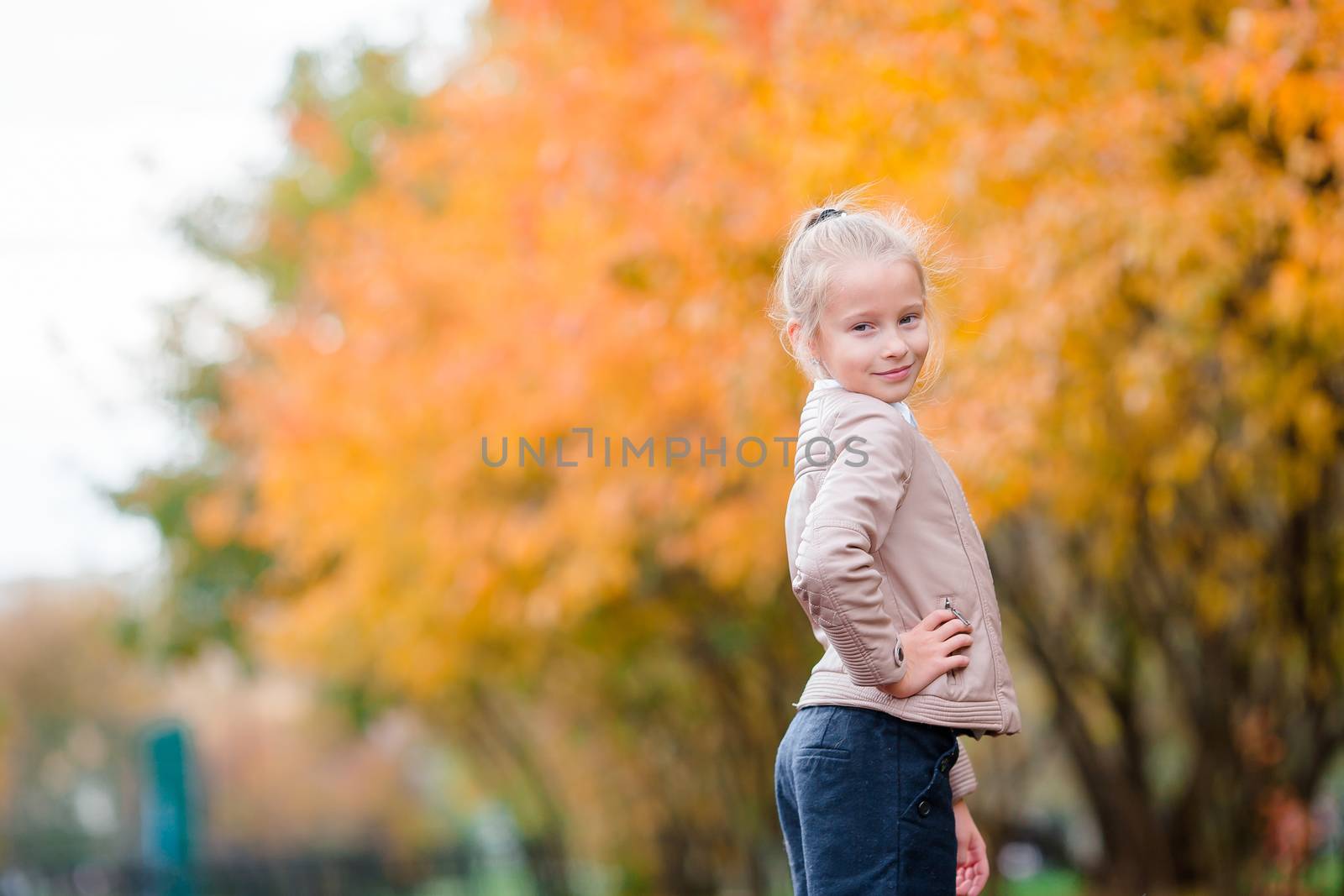 Portrait of adorable little girl with yellow trees background in fall by travnikovstudio