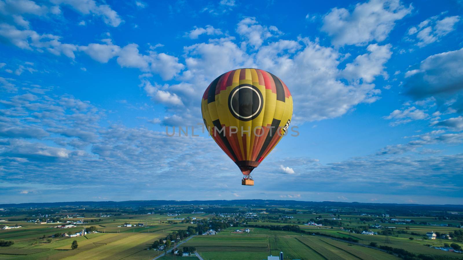 Aerial view of blue sky and multiple clouds and a hot air balloon floating thru it