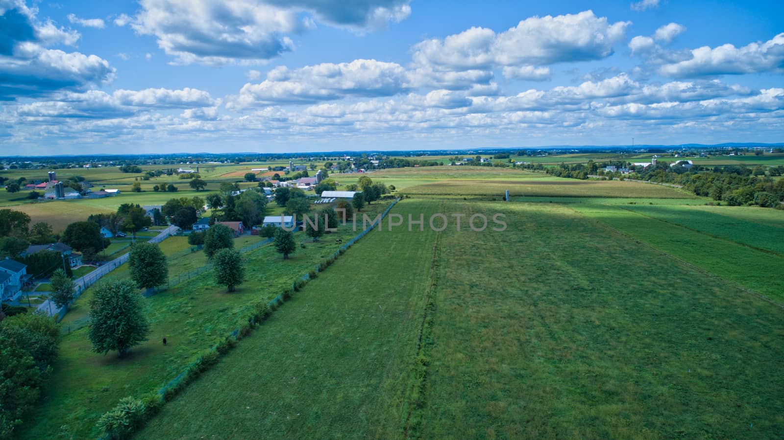 Aerial view of Amish countryside with barns and silos on a sunny summer day