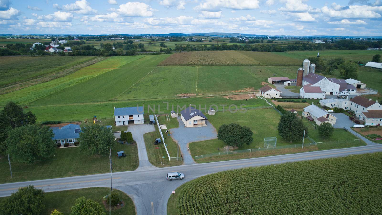 Aerial view of Amish countryside with barns and silos and a one room school house on a sunny summer day