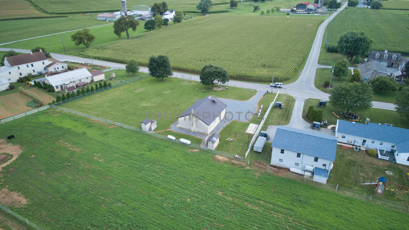 Aerial view of Amish countryside with barns and silos and a one room school house on a sunny summer day