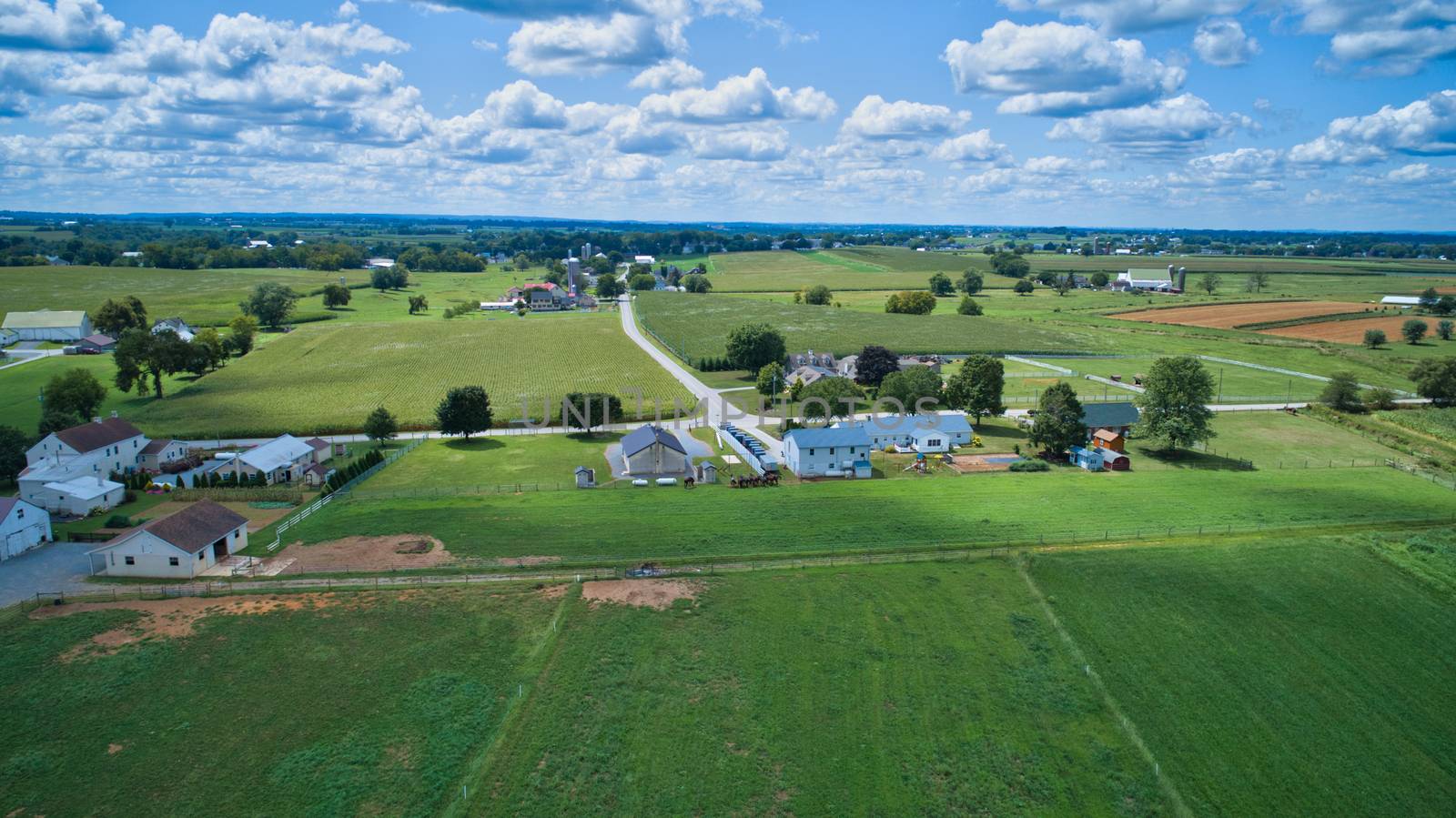 Aerial view of Amish countryside with barns and silos and a one room school house on a sunny summer day
