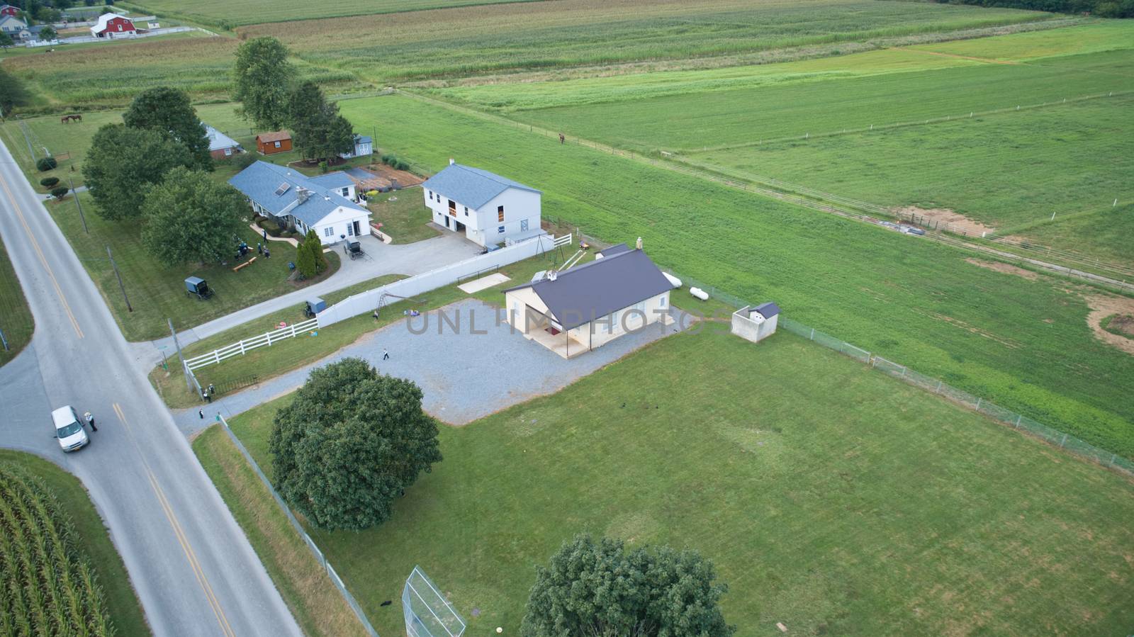 Aerial view of Amish countryside with barns and silos and a one room school house on a sunny summer day