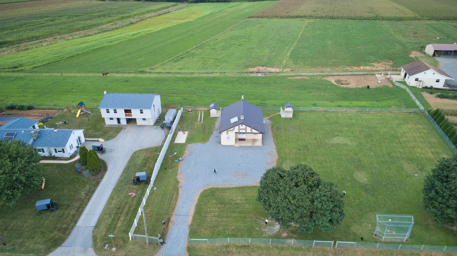 Aerial view of Amish countryside with barns and silos and a one room school house on a sunny summer day