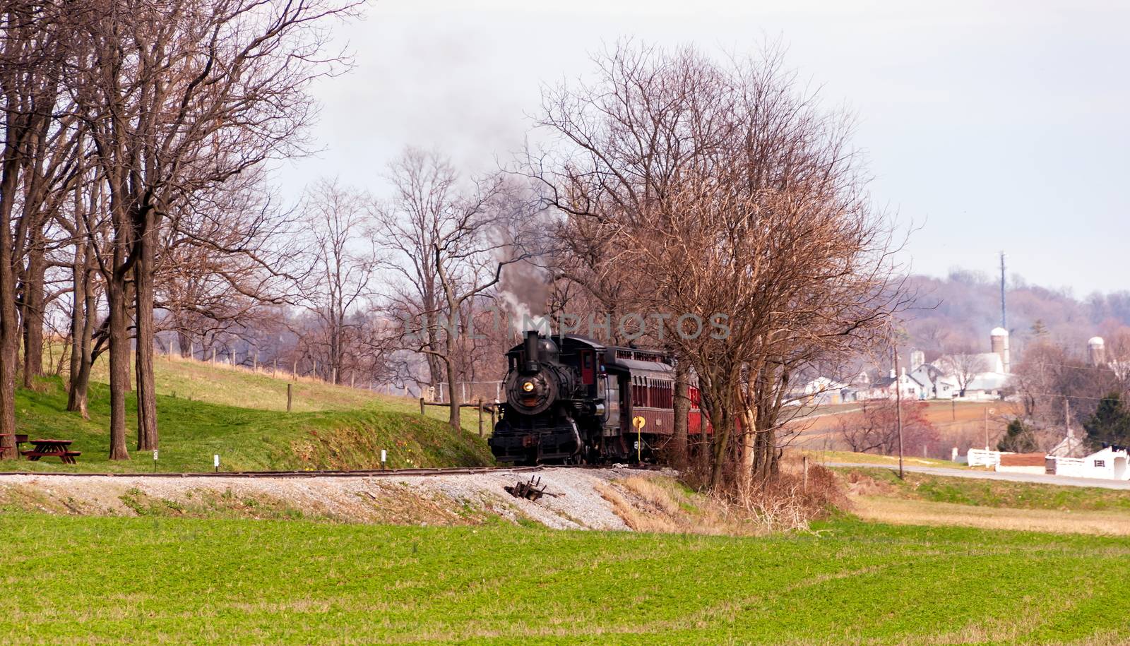 Steam train pulling passenger cars on a winter day