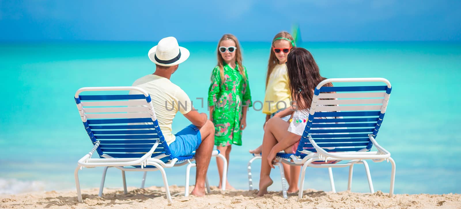 Family of four on beach holidays by travnikovstudio