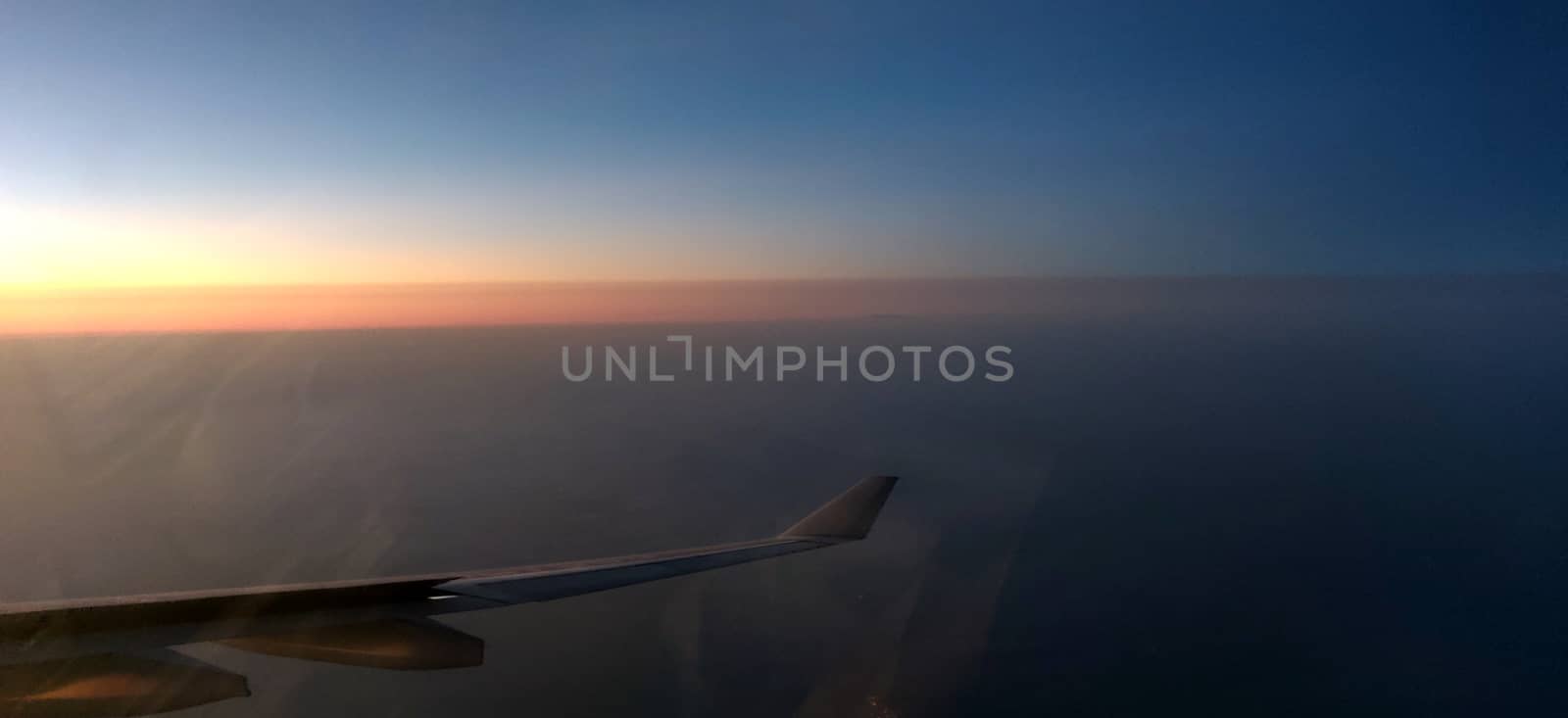 Airplane wing amidst setting sun in horizon by mshivangi92