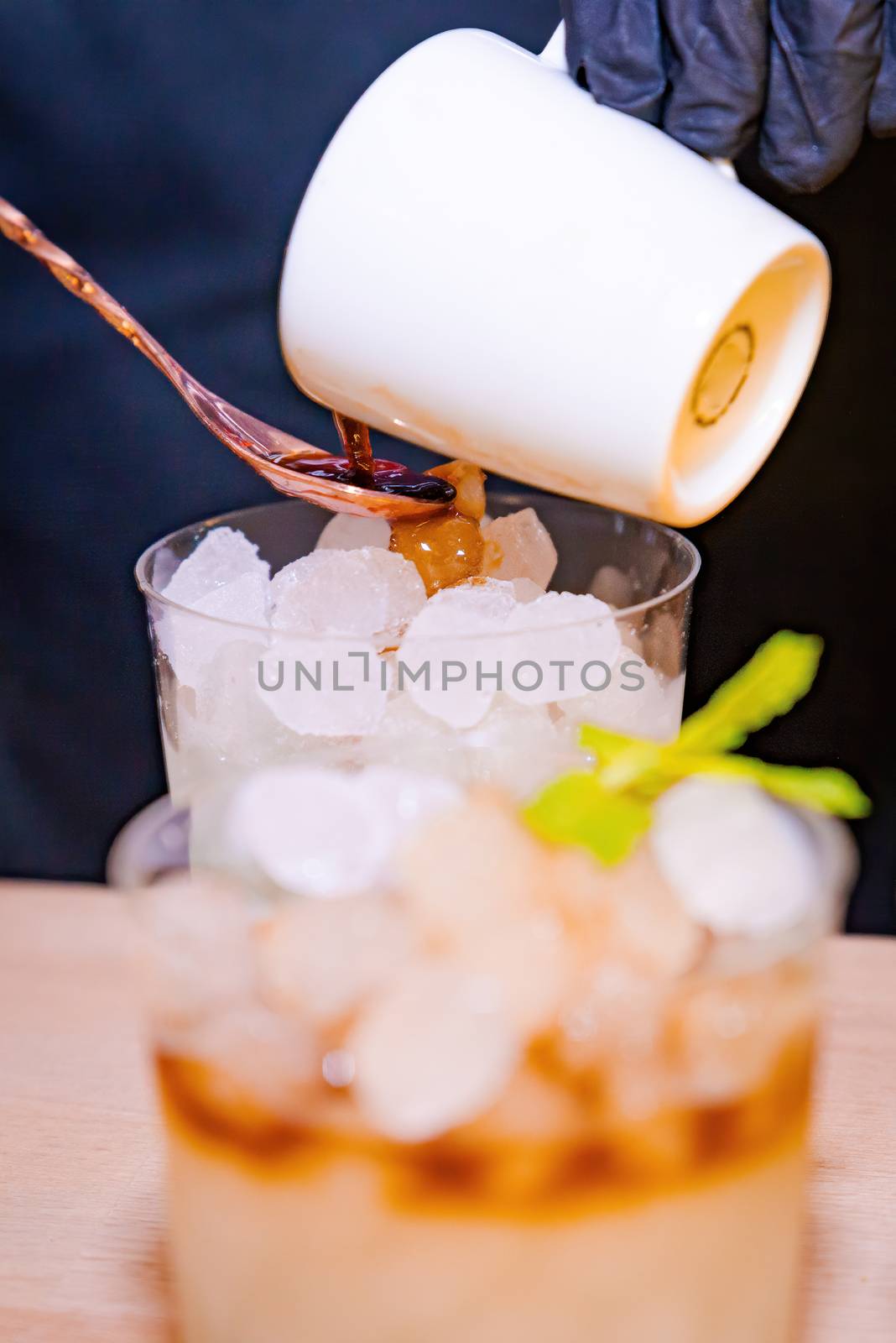 Barman haceiendo un coctel de cafe y un mojito en primer plano con su vaso con hielo y hierbabuena