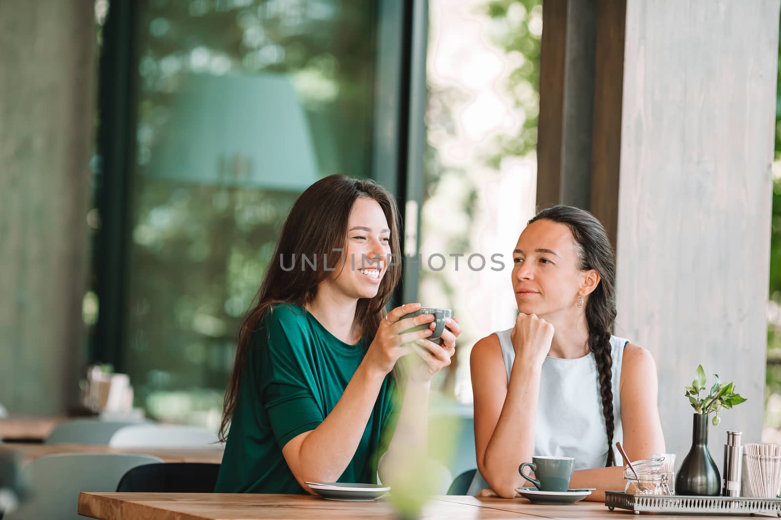Happy smiling young women with coffee cups at cafe. by travnikovstudio