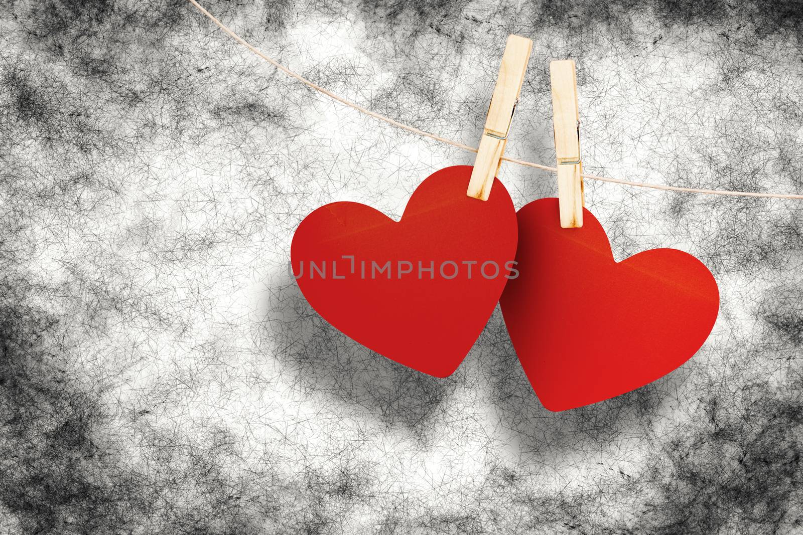 Hearts hanging on line against grey background