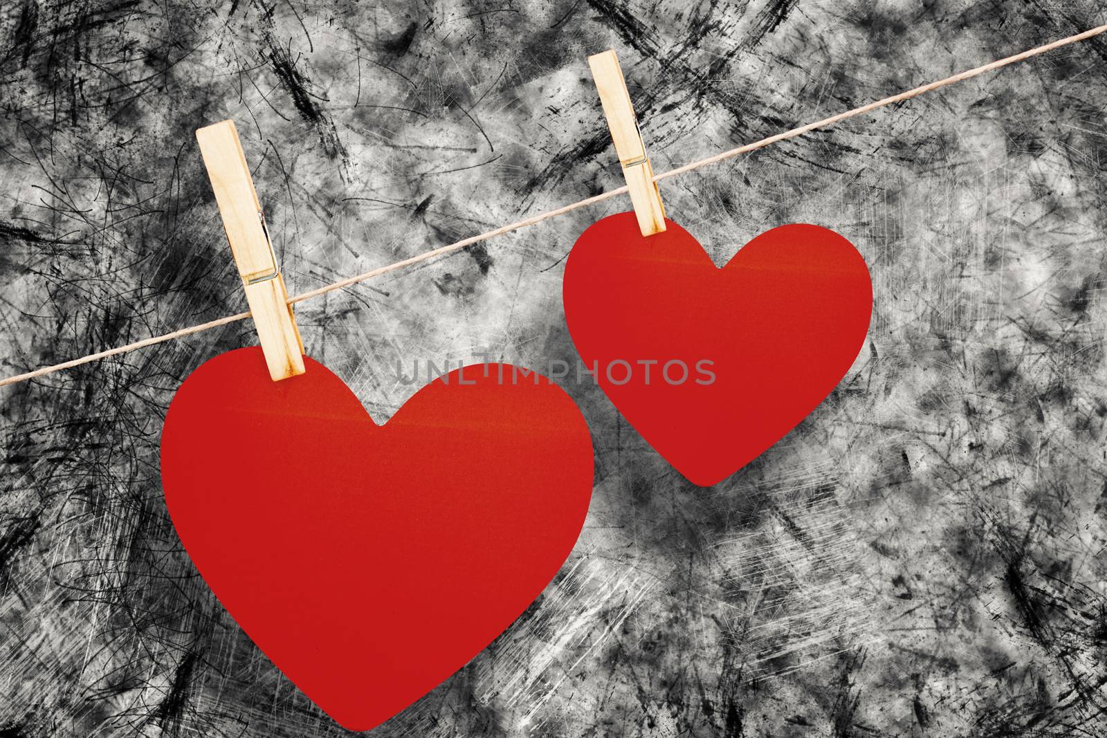 Hearts hanging on a line against grey background