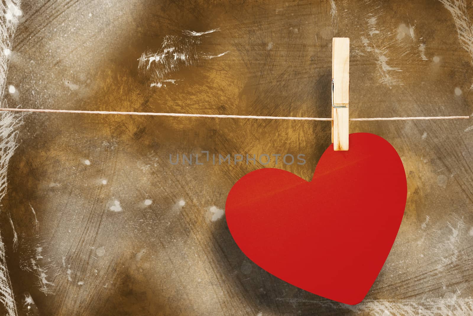 Heart hanging on line against orange background