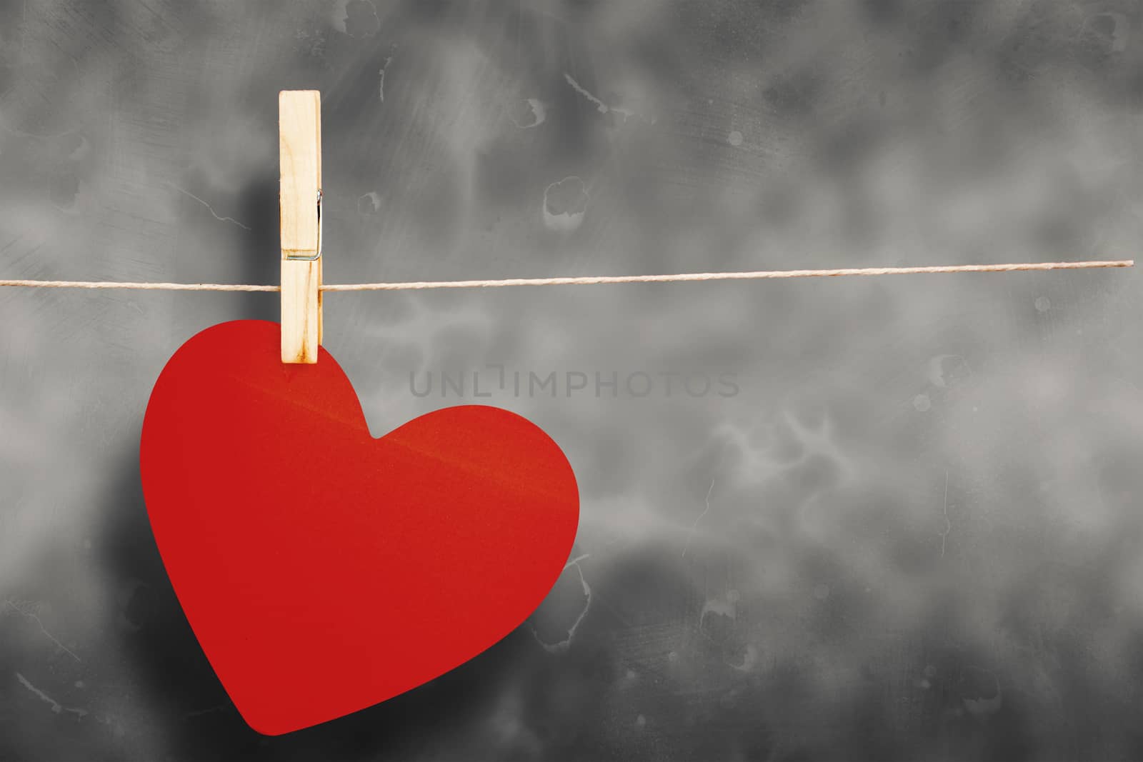 Heart hanging on line against grey background