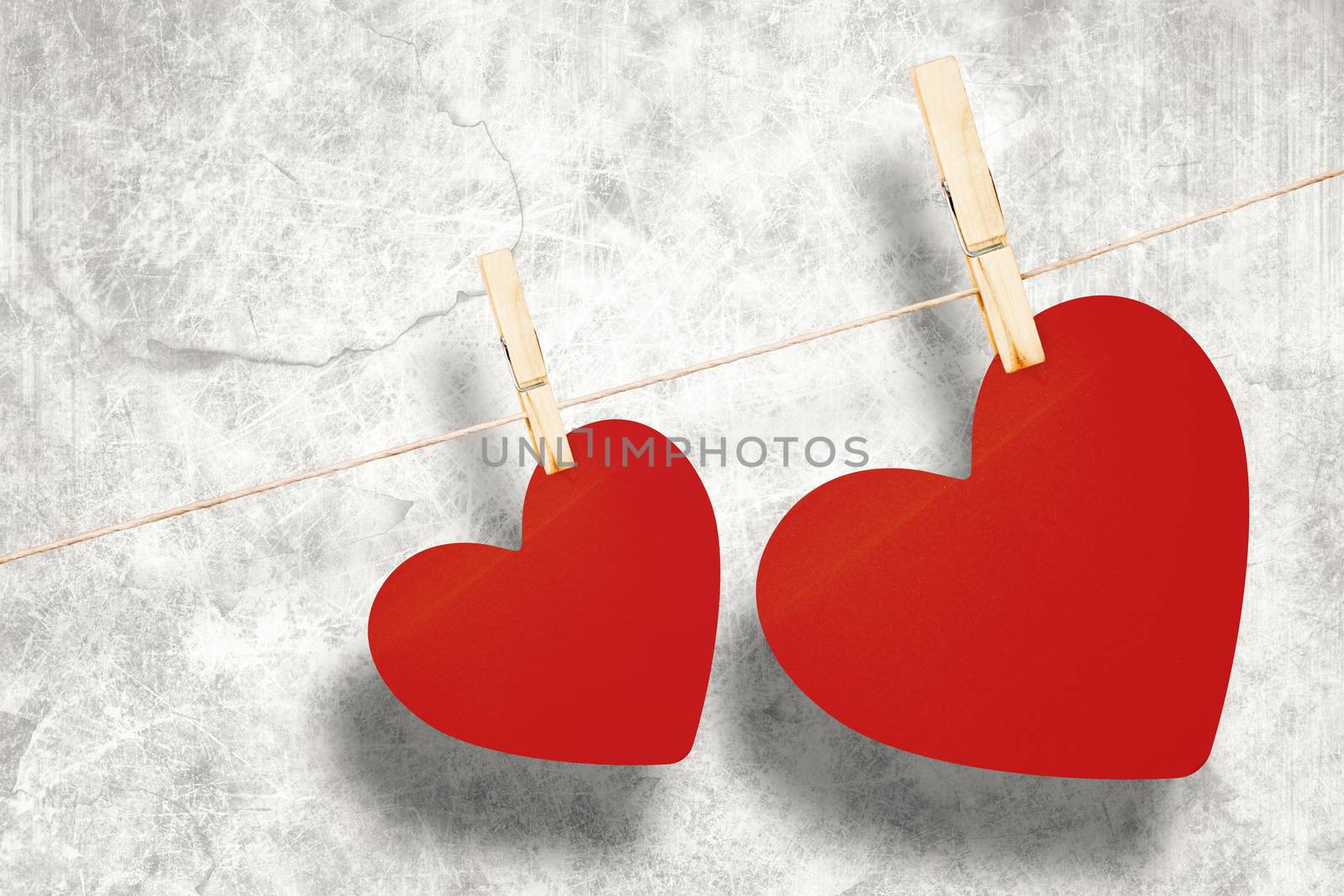 Hearts hanging on a line against grey background