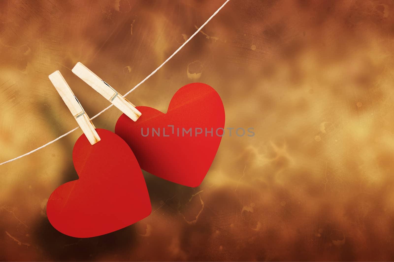 Hearts hanging on line against orange background