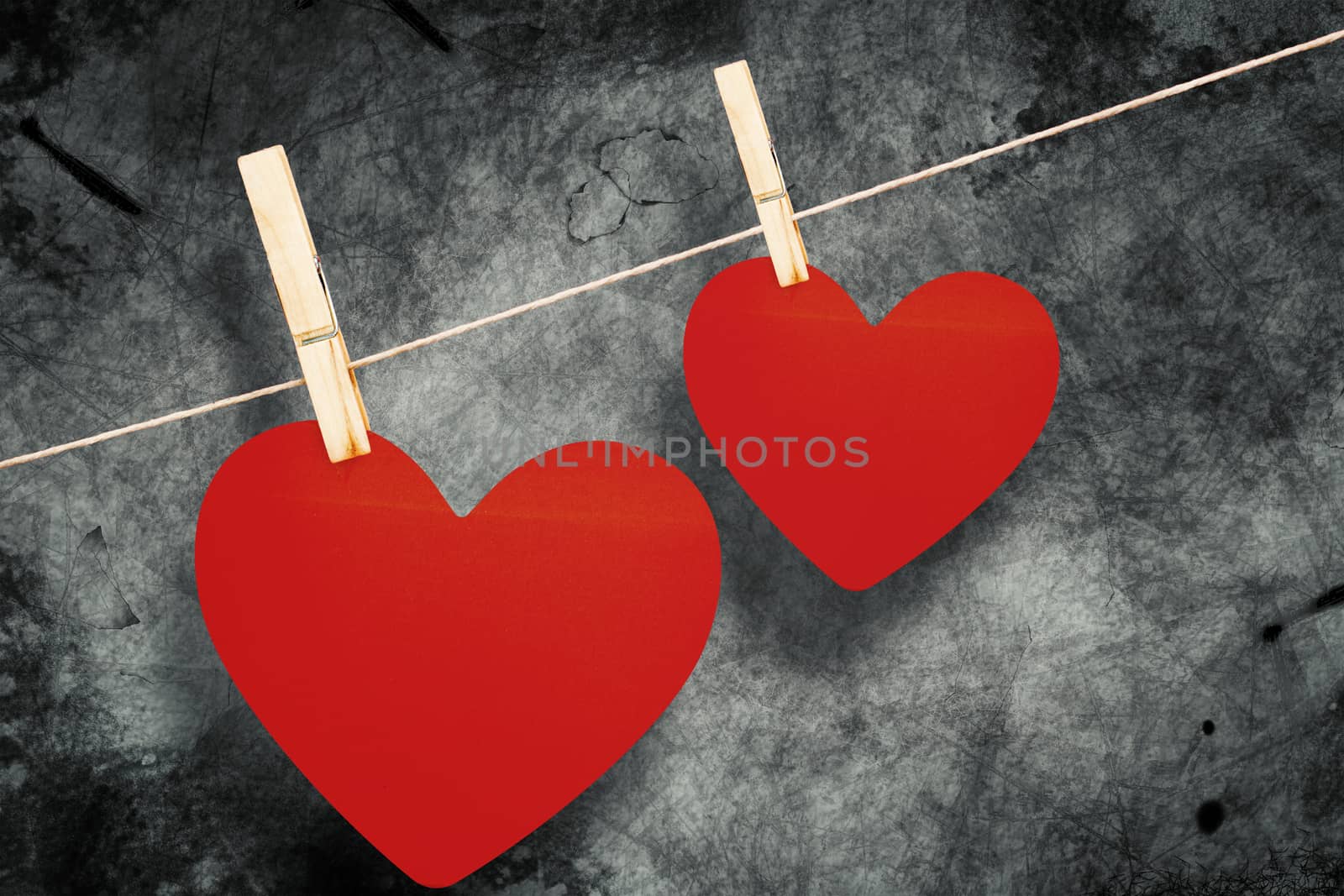Hearts hanging on a line against grey background