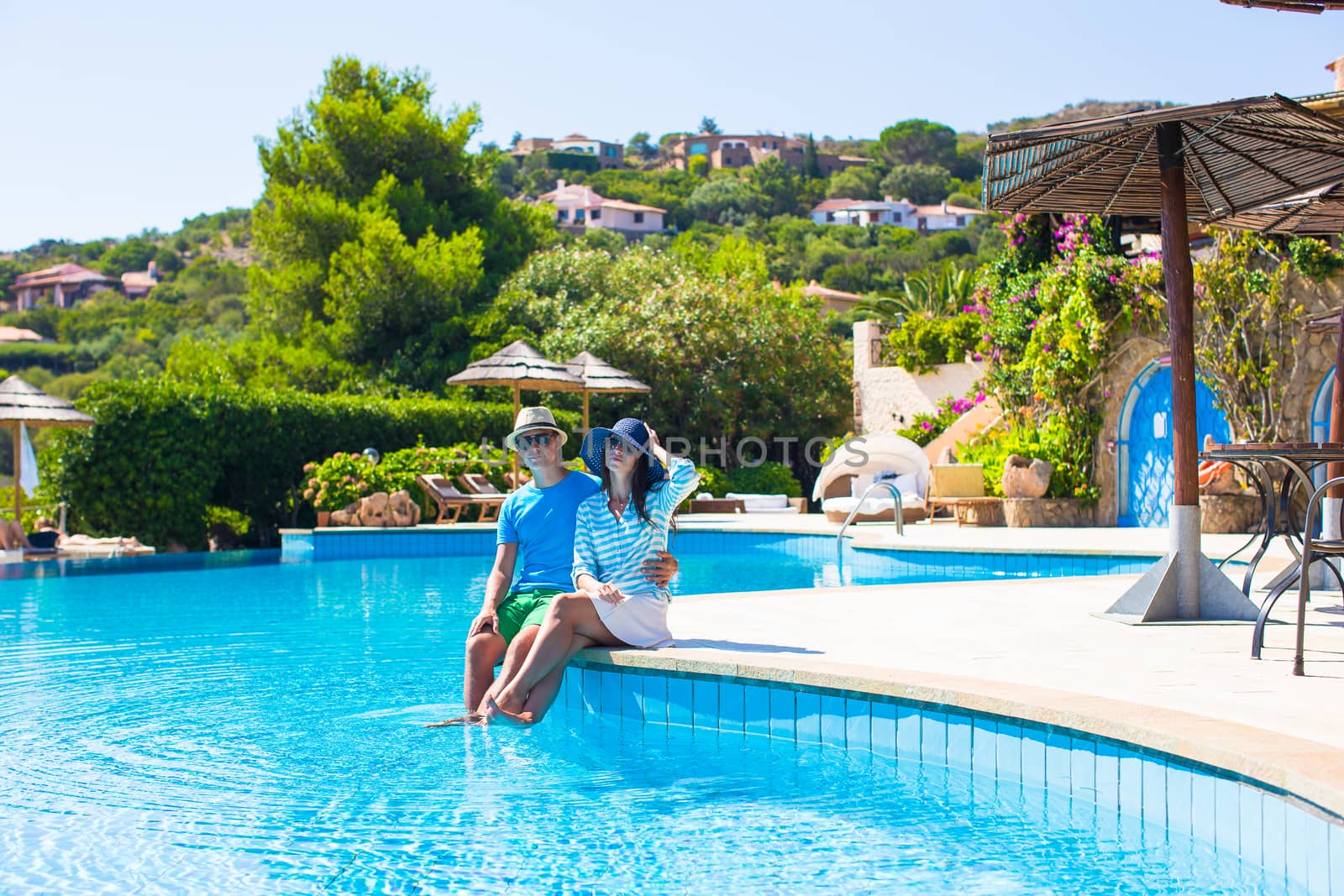 Lovely young romantic couple relaxing by swimming pool by travnikovstudio