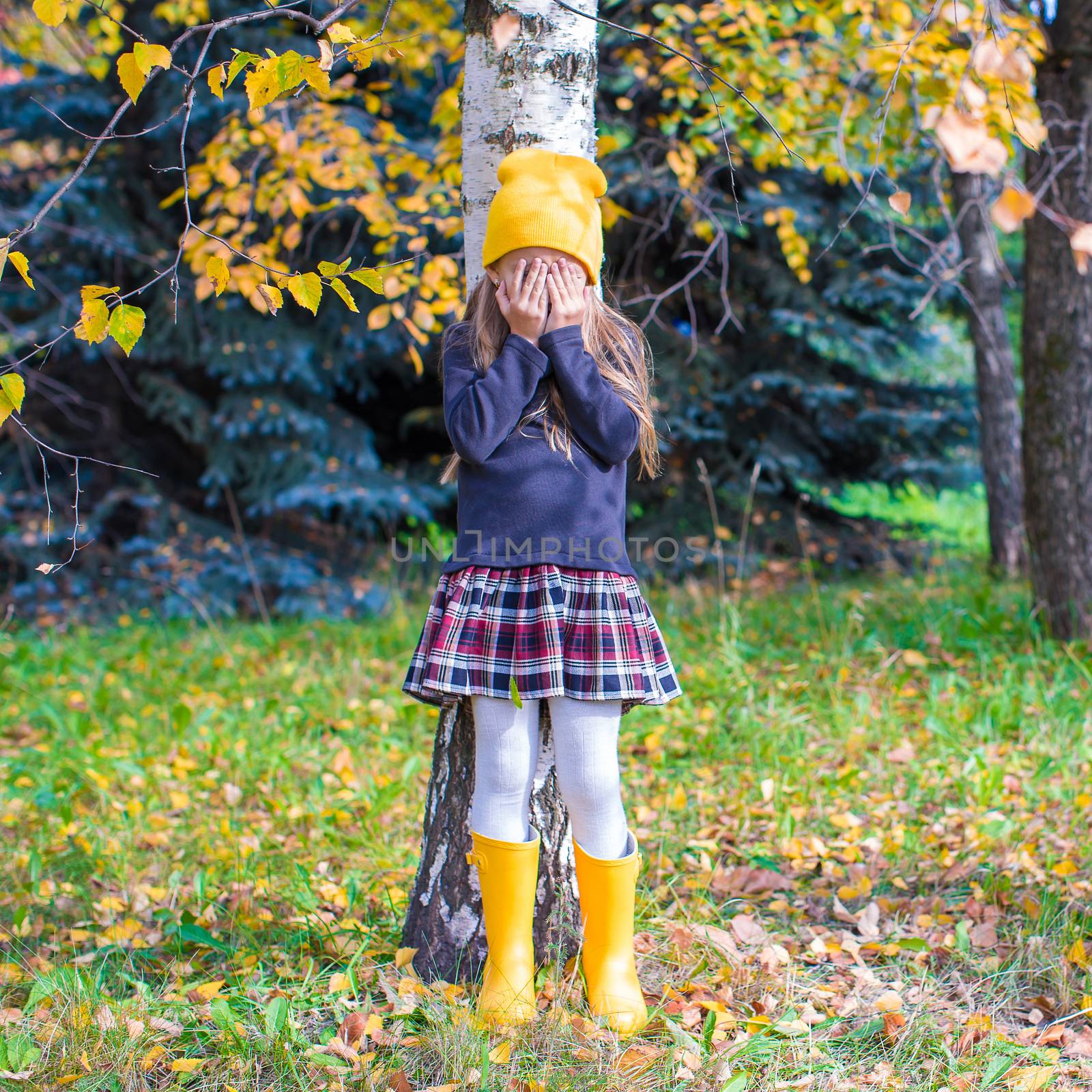 Little girl playing hide and seek in autumn forest by travnikovstudio