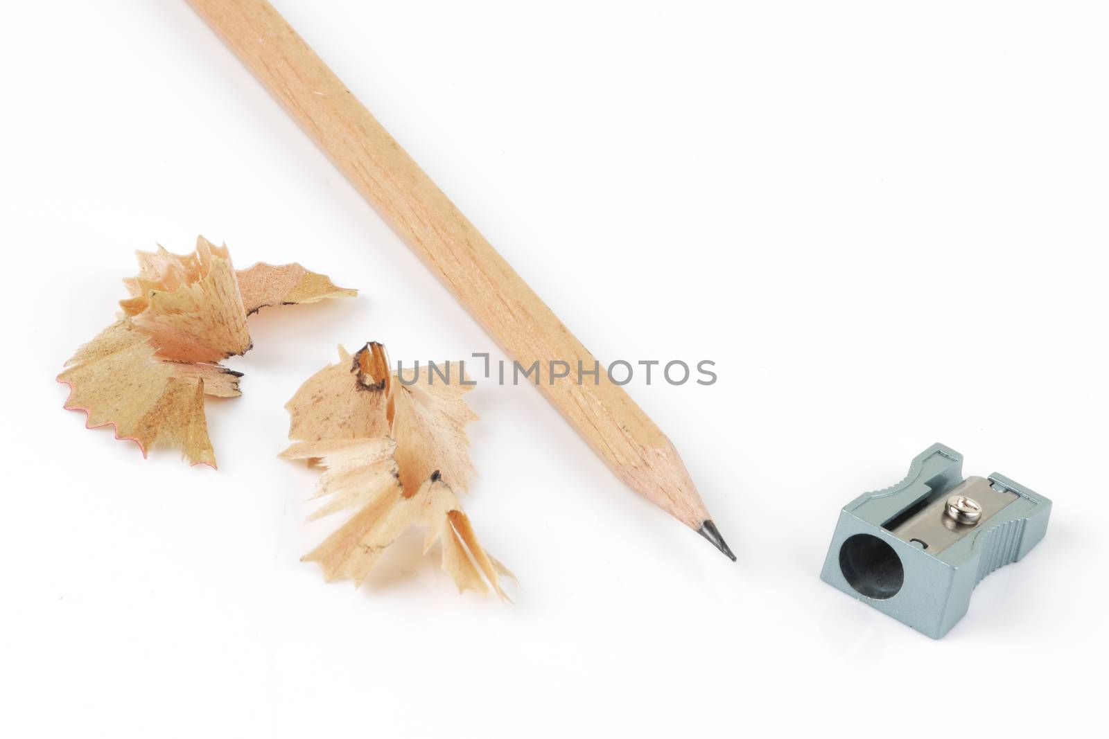 A top view of pencil and sharpener with shavings on white