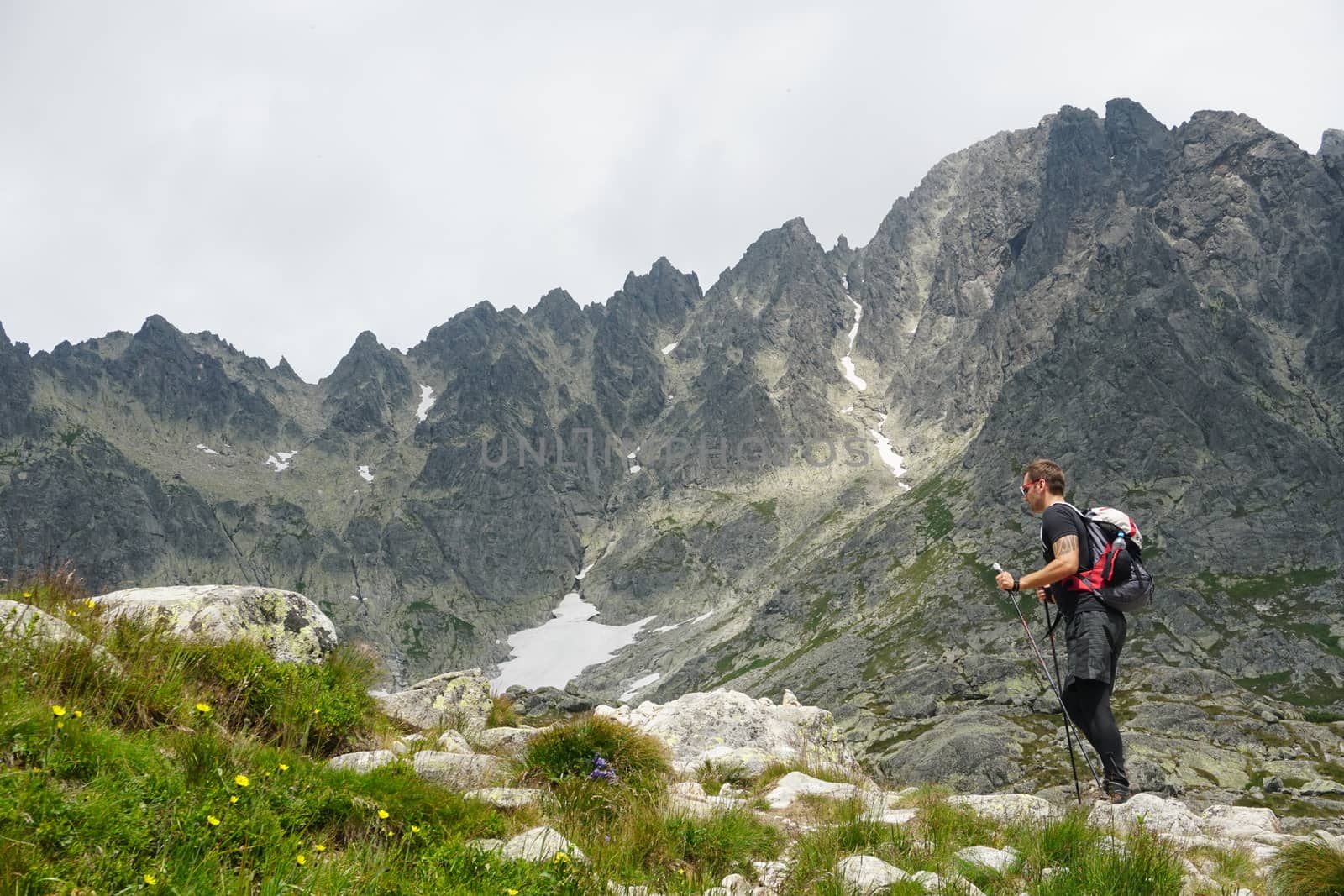 Man with hiking equipment walking in High Tatra mountain in Slovakia. Majestic View on the Lomnicky Stit in the background