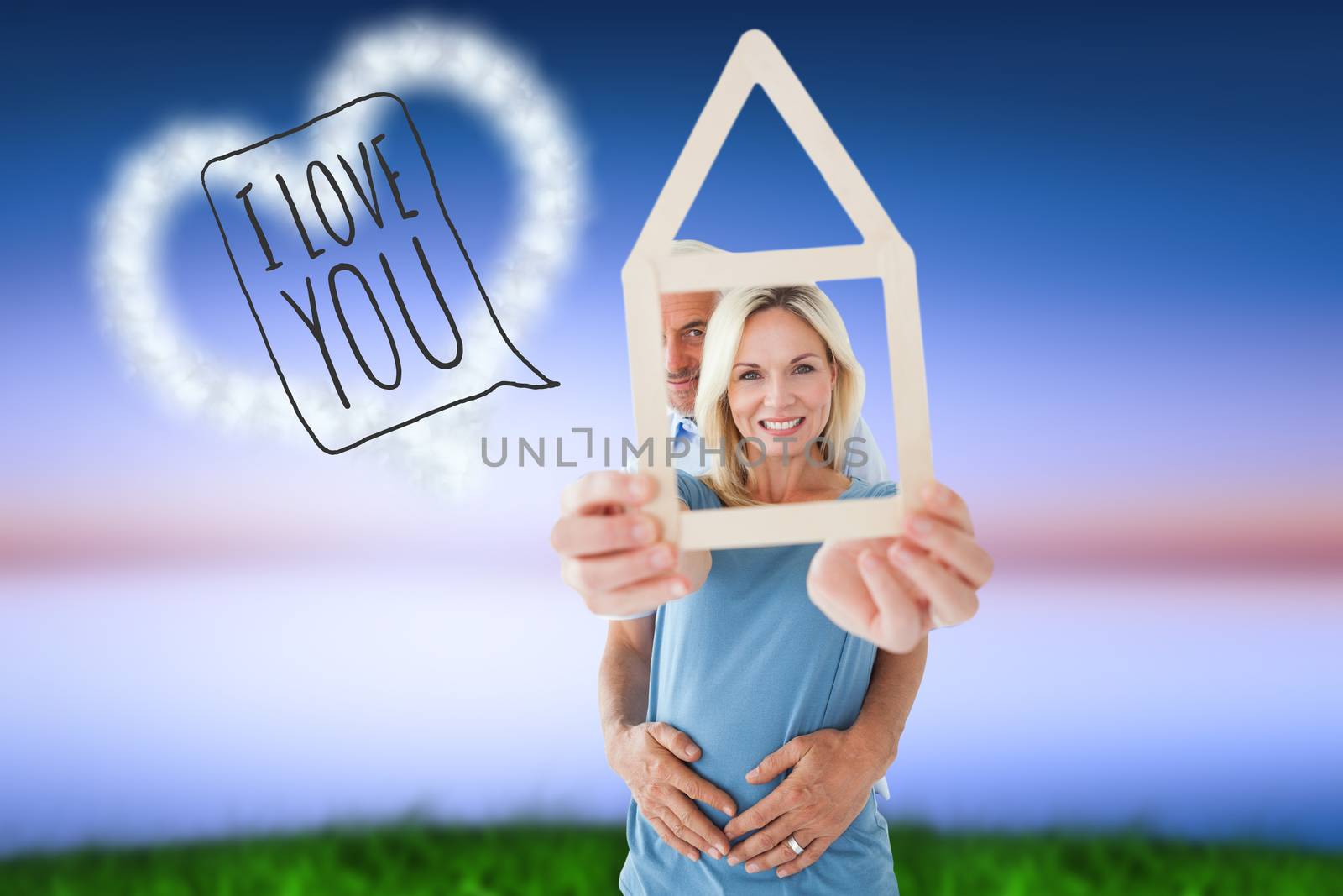 Happy couple holding house outline  against green grass under blue and purple sky