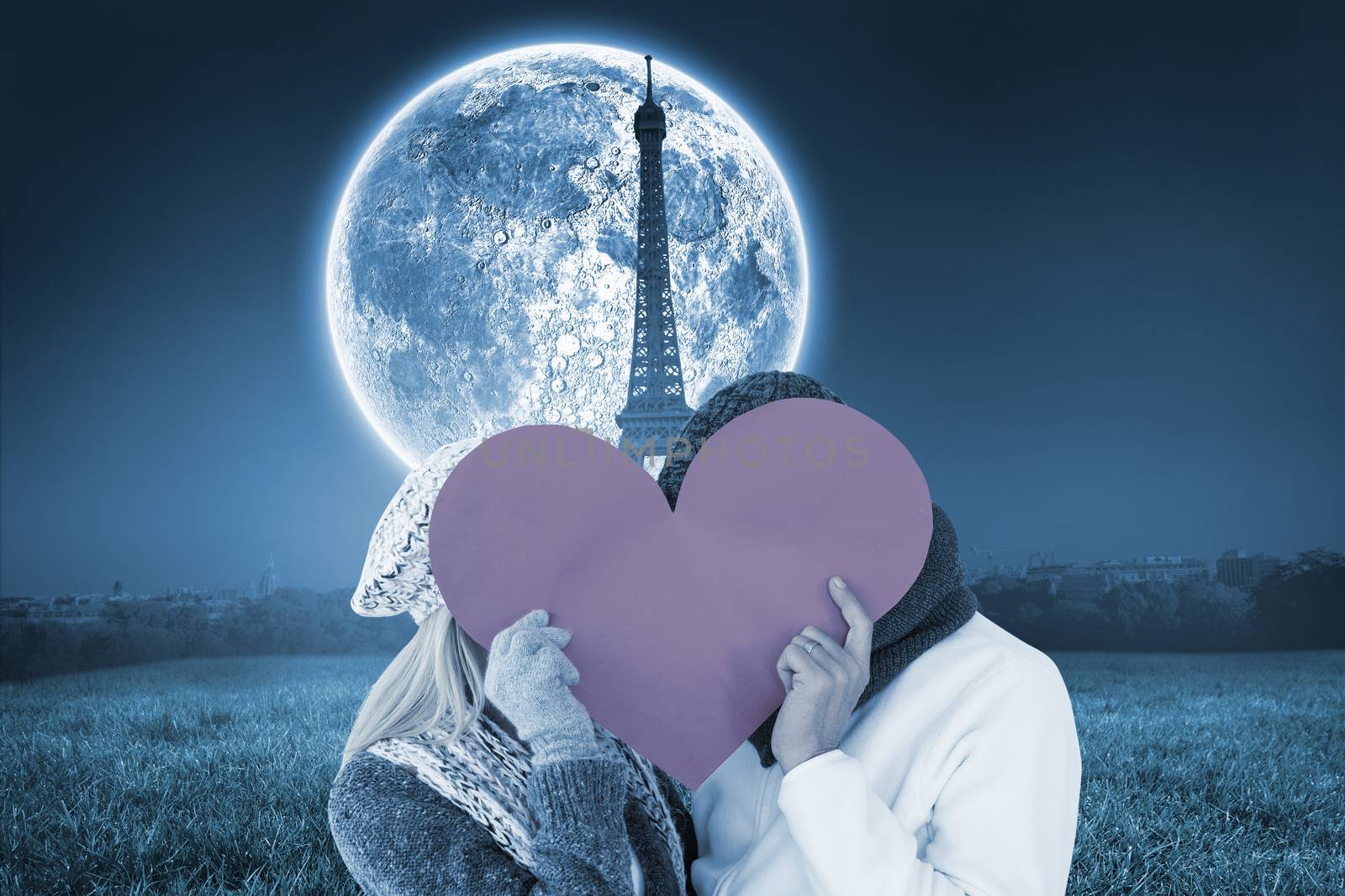 Couple in winter fashion posing with heart shape against large moon over paris