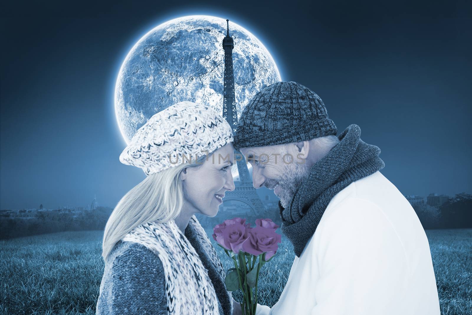 Smiling couple in winter fashion posing with roses against large moon over paris