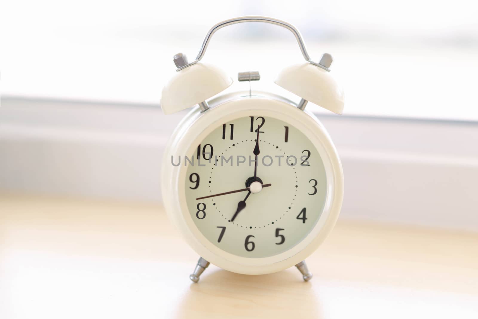 Alarm clock on white table with soft light in the morning, selective
