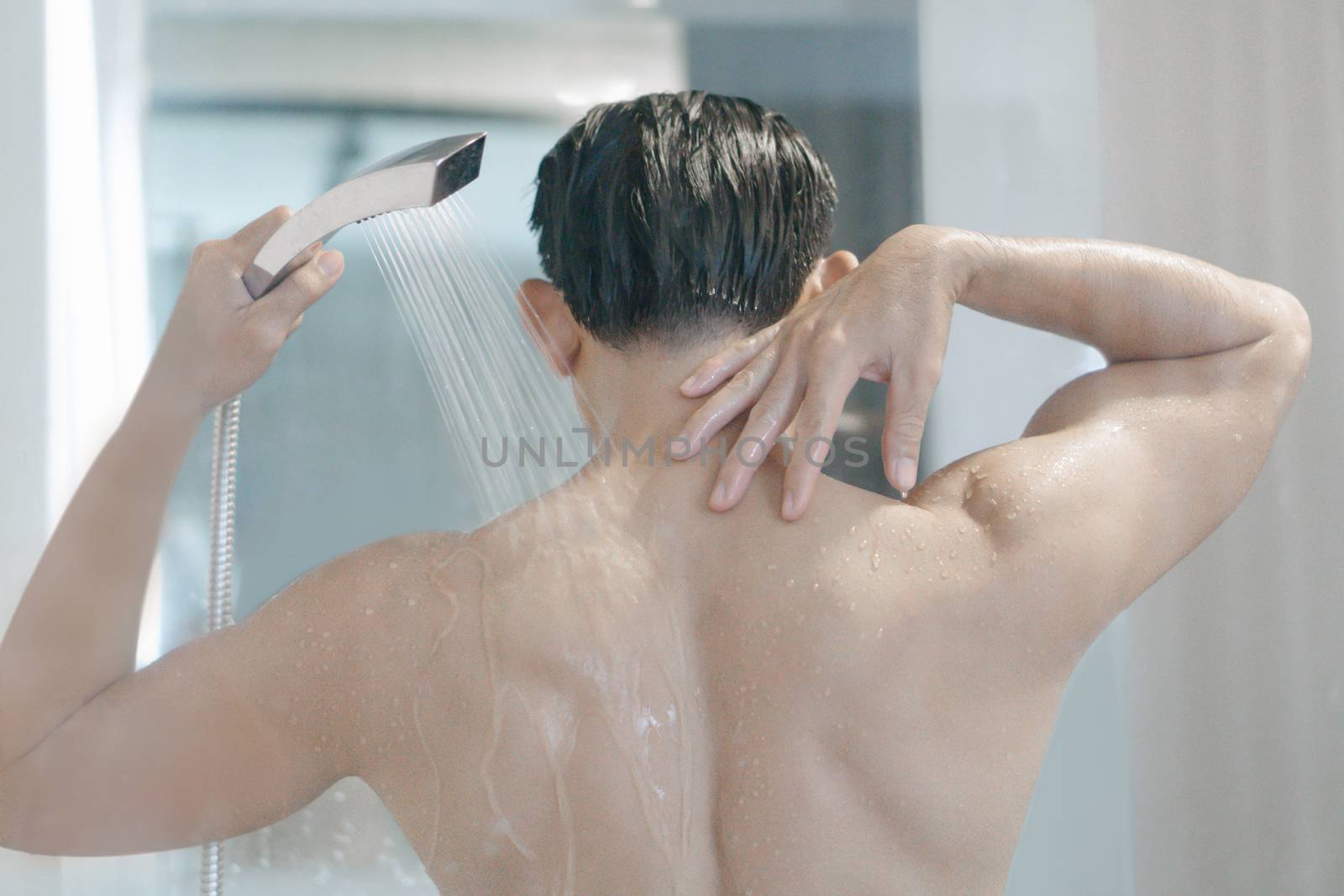 Closeup young man washing hair with with shampoo in the bathroom, vintage tone, selective focus