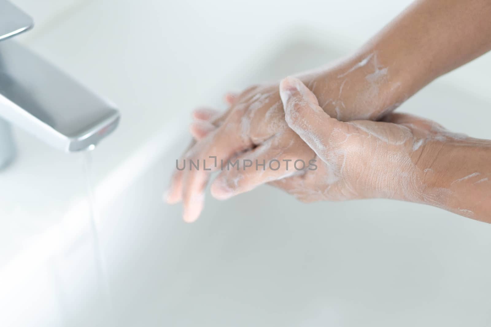 Closeup woman's hand washing with soap in bathroom, selective focus