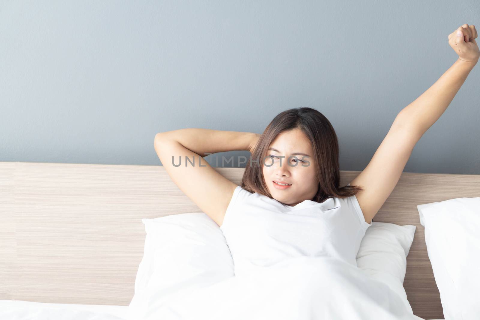 Close up asian woman smiling with happy face lying on white bed in the morning, selective focus