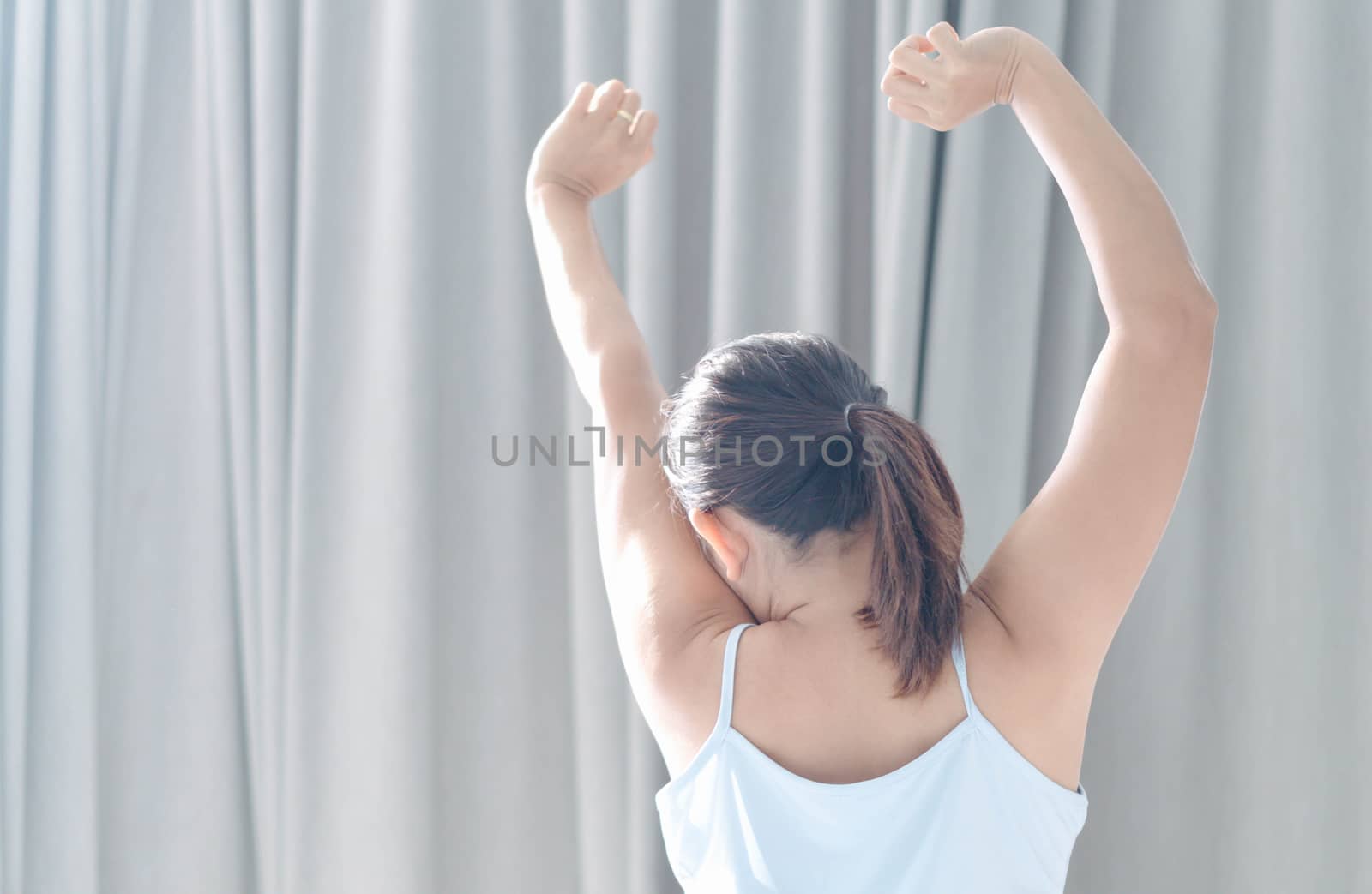 Close up woman sitting on the bed and stretching after waking up for relax in the morning with over light background