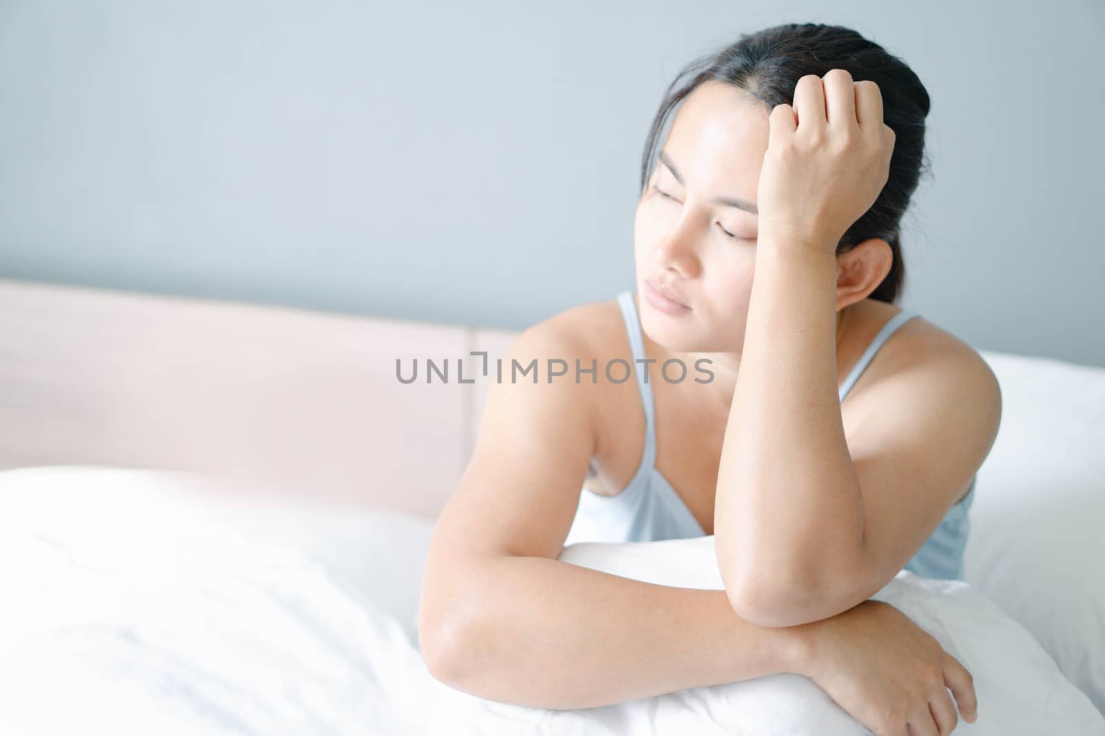 Closeup woman sitting on bed in the bedroom with thinking or depressed feeling, selective focus