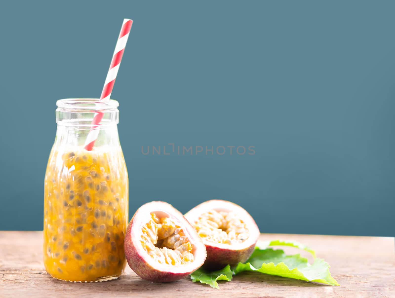 Glass bottle of passion fruit juice wood table isolated on grey background, food healthy concept