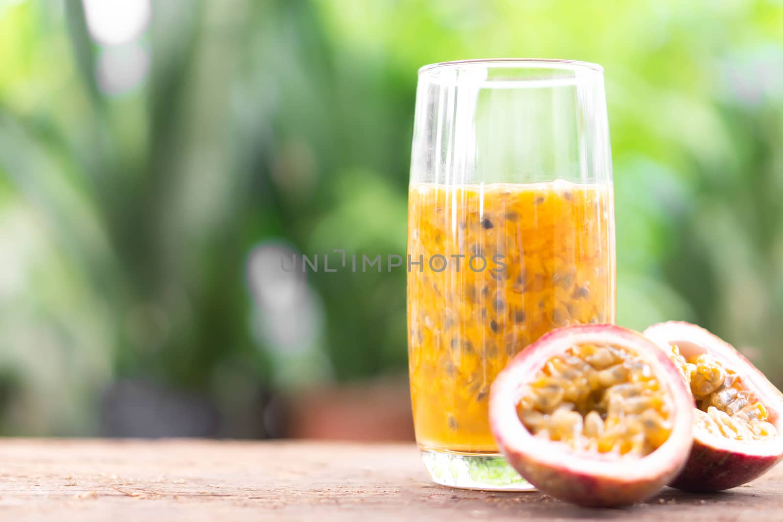 Glass of passion fruit juice wood table with green nature background, food healthy concept, selective focus