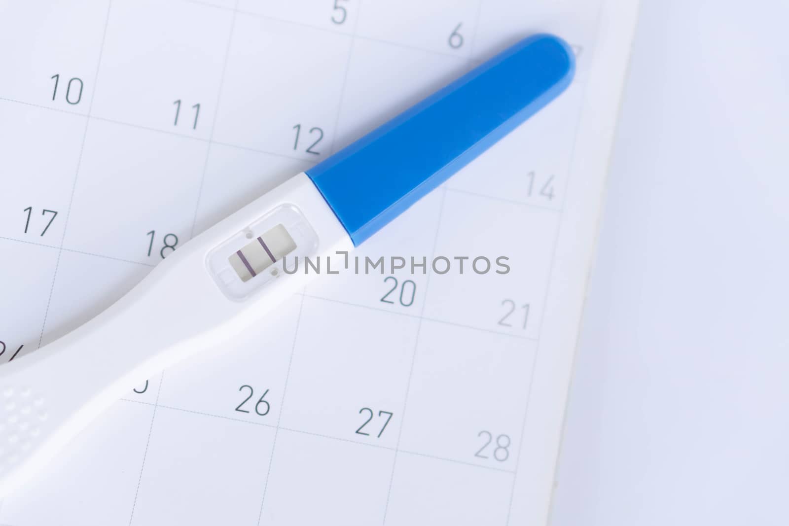 Pregnancy test on calendar background, health care concept